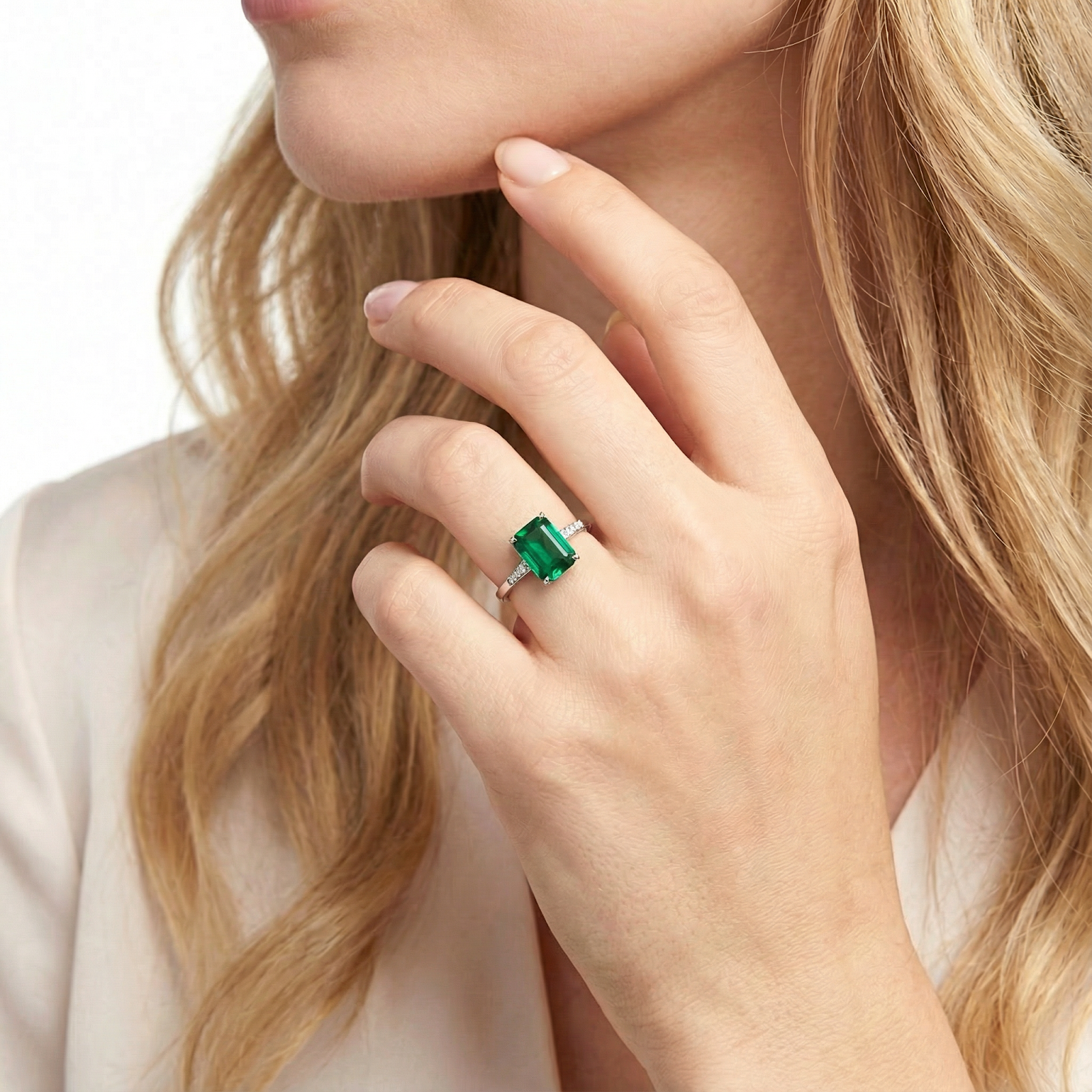 Emerald-cut simulated emerald ring in sterling silver worn on a woman's hand.