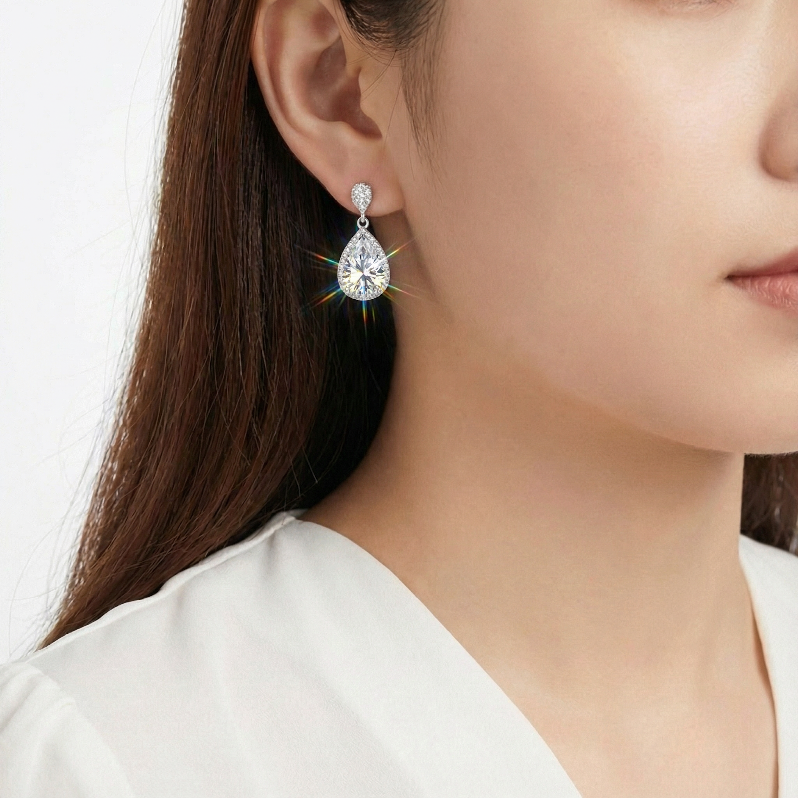 Woman wearing a sparkling sterling silver teardrop earring with a round-cut zirconia stone.