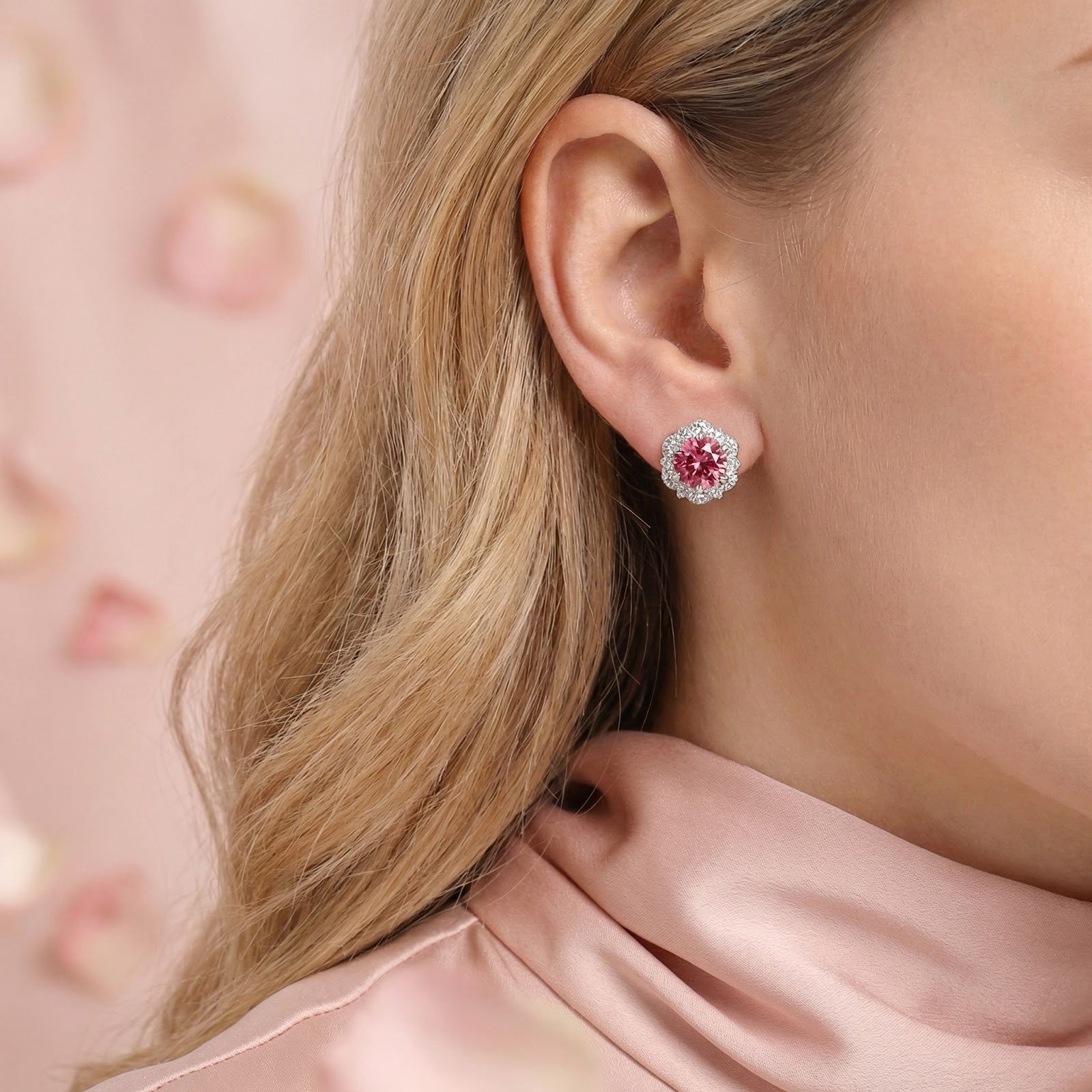 Close-up of a simulated pink tourmaline halo stud earring in sterling silver worn on a model's ear.