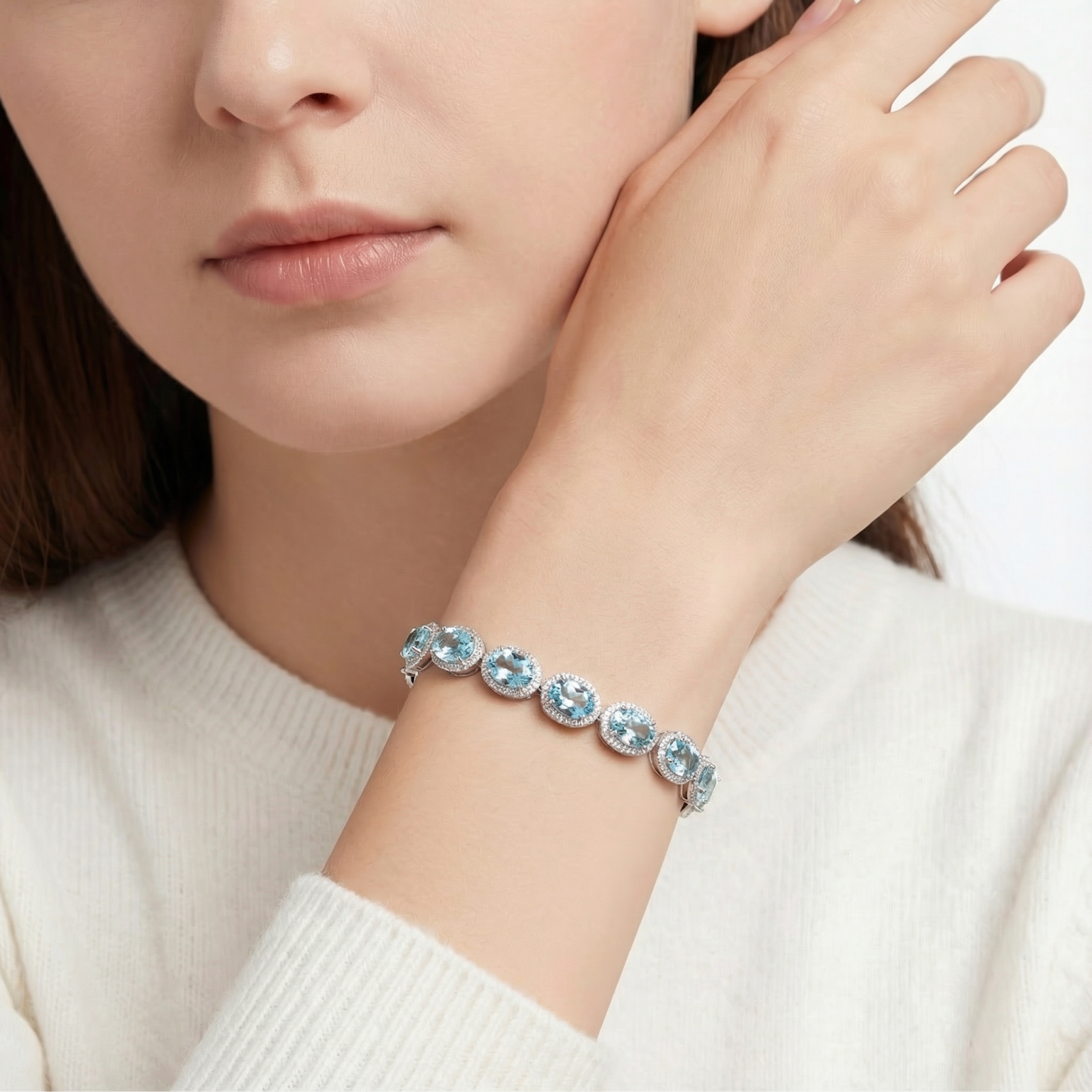Thalassa halo bracelet with oval simulated aquamarine stones in sterling silver worn on a woman's wrist.