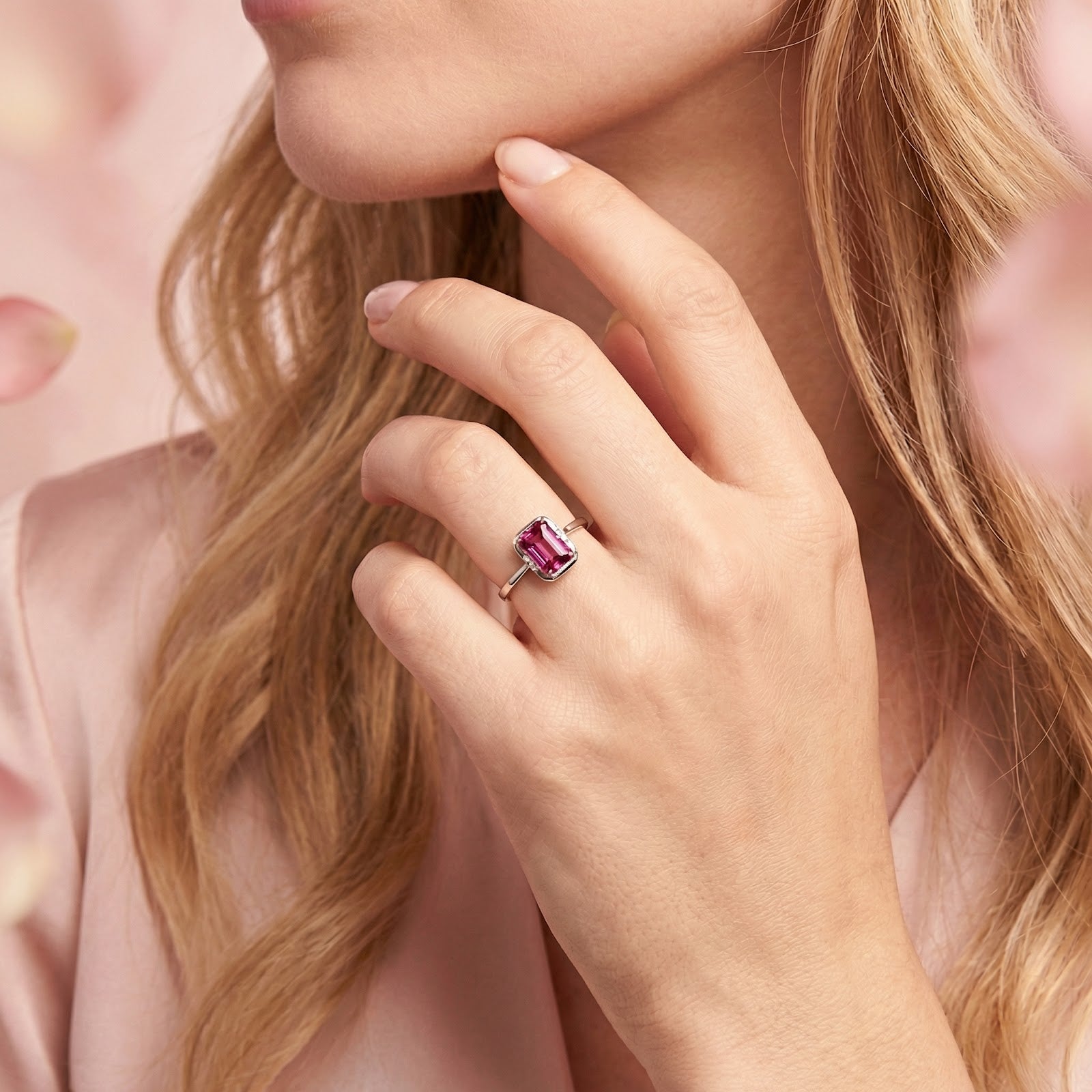 Lifestyle shot of a model wearing the emerald-cut pink tourmaline silver ring with a pink silk outfit.