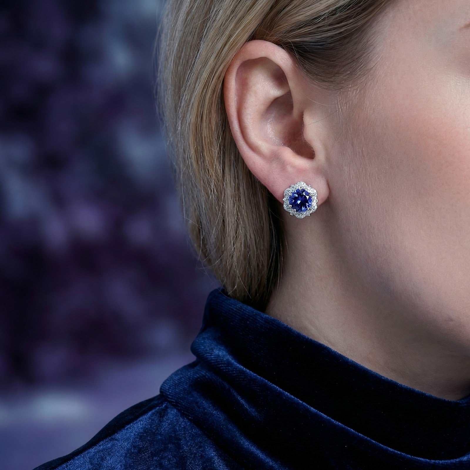 Sidraea Blossom sterling silver halo earring with a blue simulated tanzanite stone worn on a model's ear.