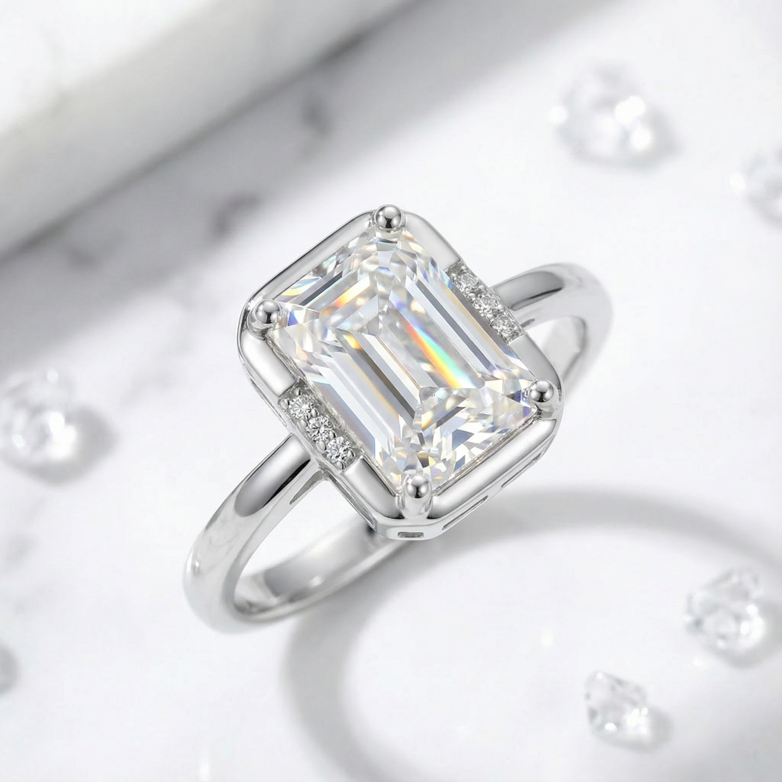 Close-up view of an emerald-cut moissanite stone and sterling silver setting with side accents.