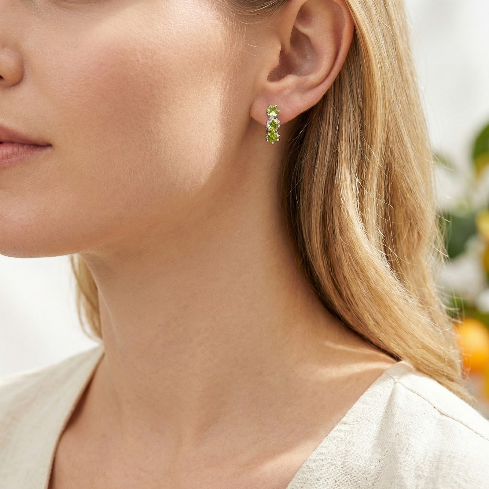 Model wearing the sterling silver Elianise star hoop earrings with vibrant green star-cut peridot stones.