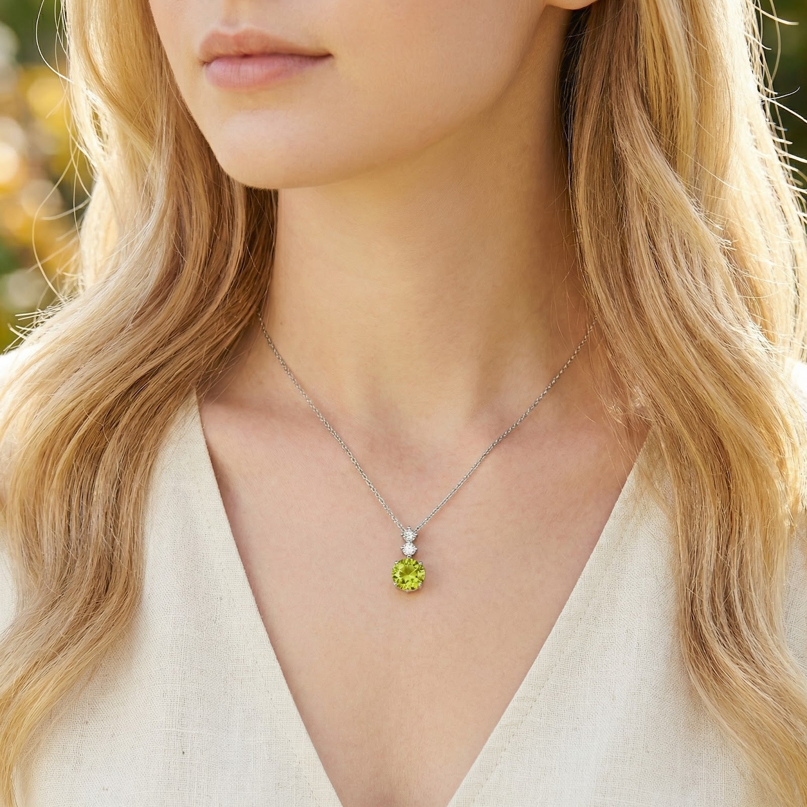 August birthstone necklace with a lime-green simulated peridot pendant worn by a model.