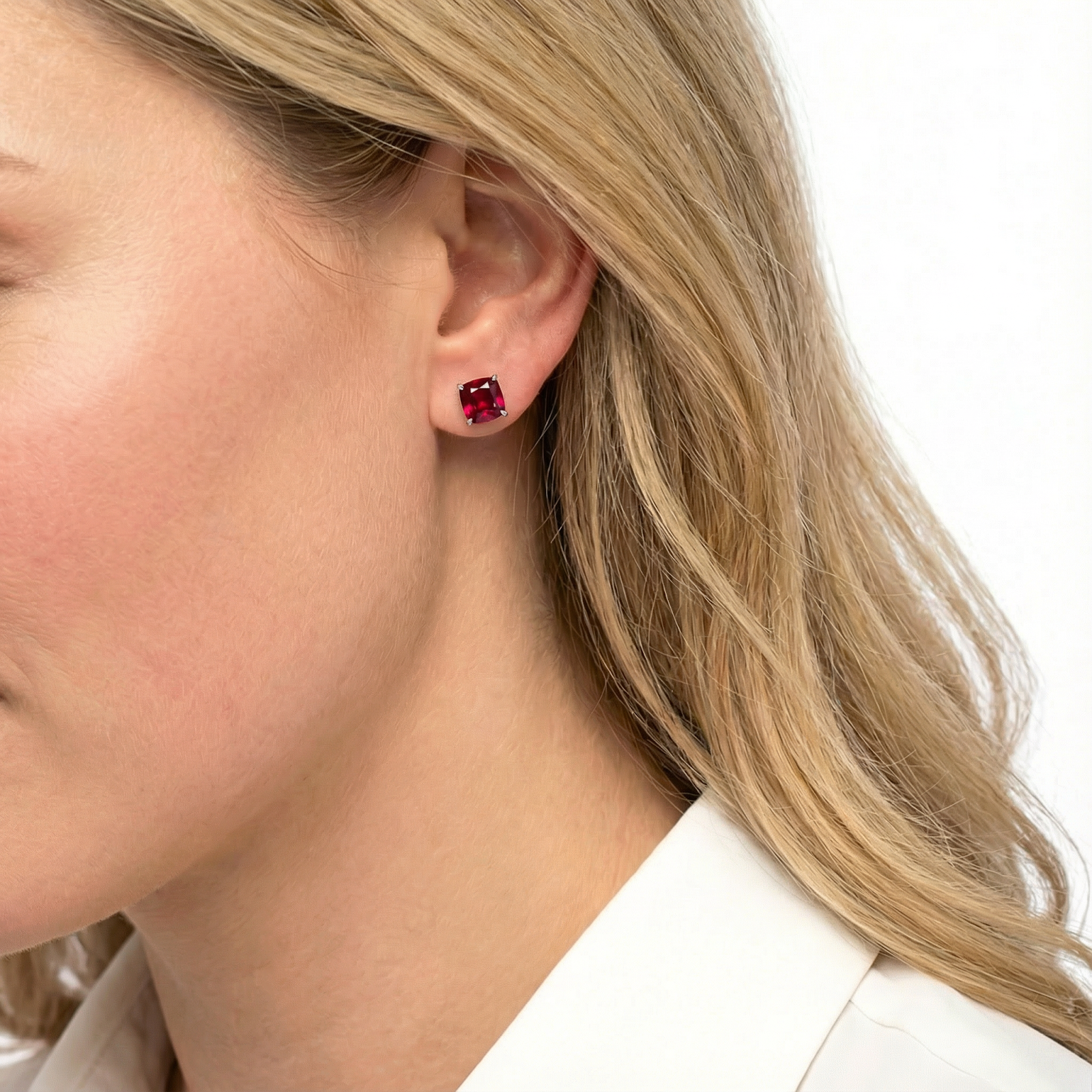 Side view of a woman wearing a square pigeon blood simulated ruby stud earring in rose gold.