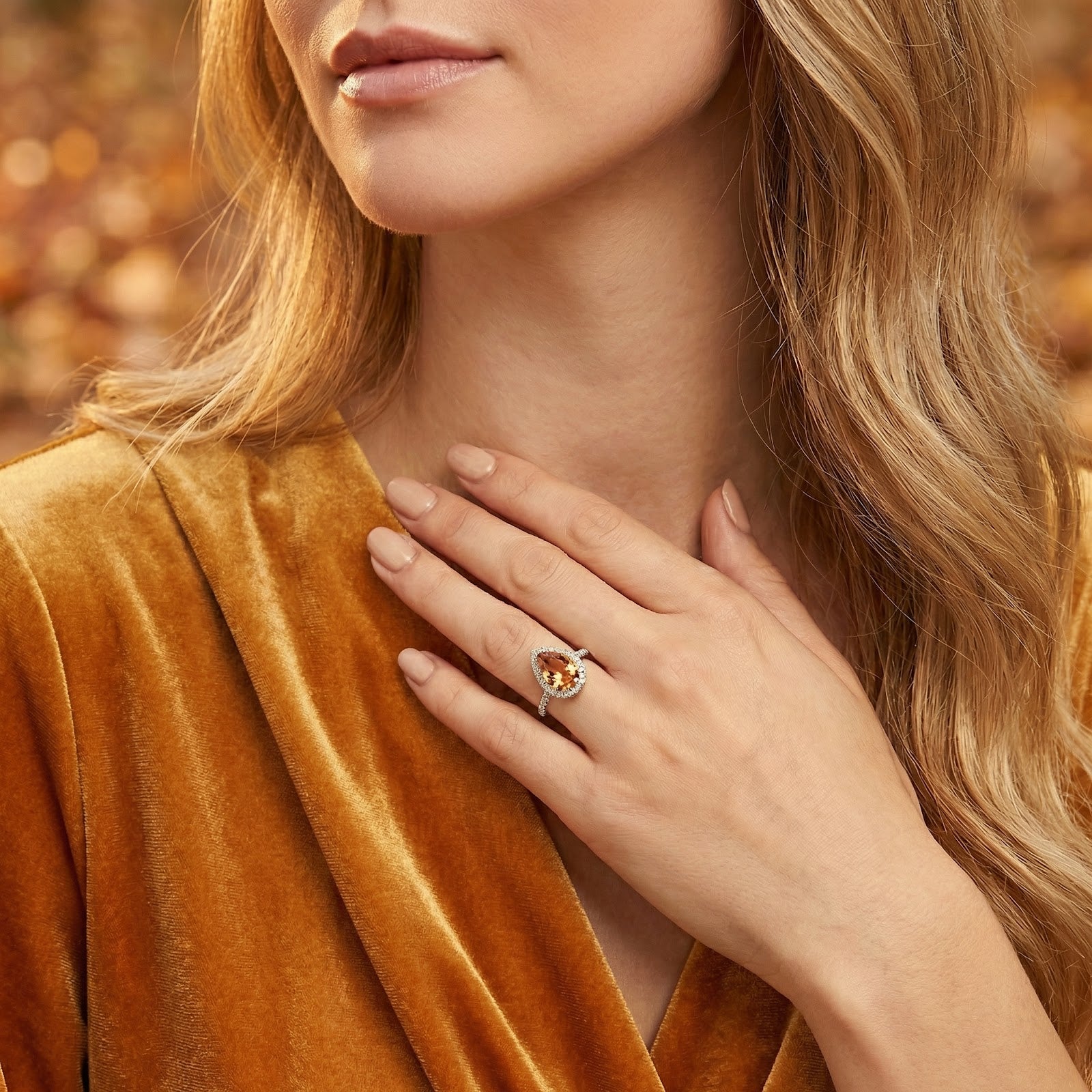 Model wearing the S925 sterling silver pear-cut simulated topaz ring on her hand, resting against a gold velvet top.