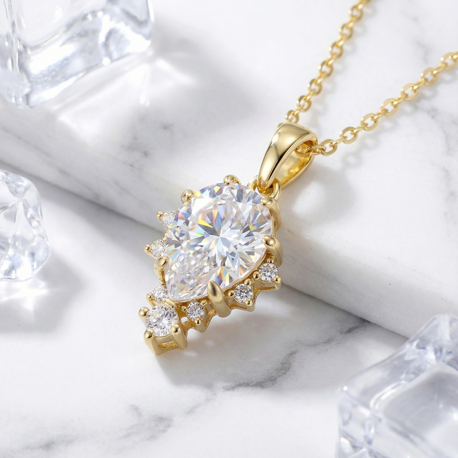 Angled view of the pear-cut zirconia necklace in 18K gold vermeil on marble with ice cube accents.