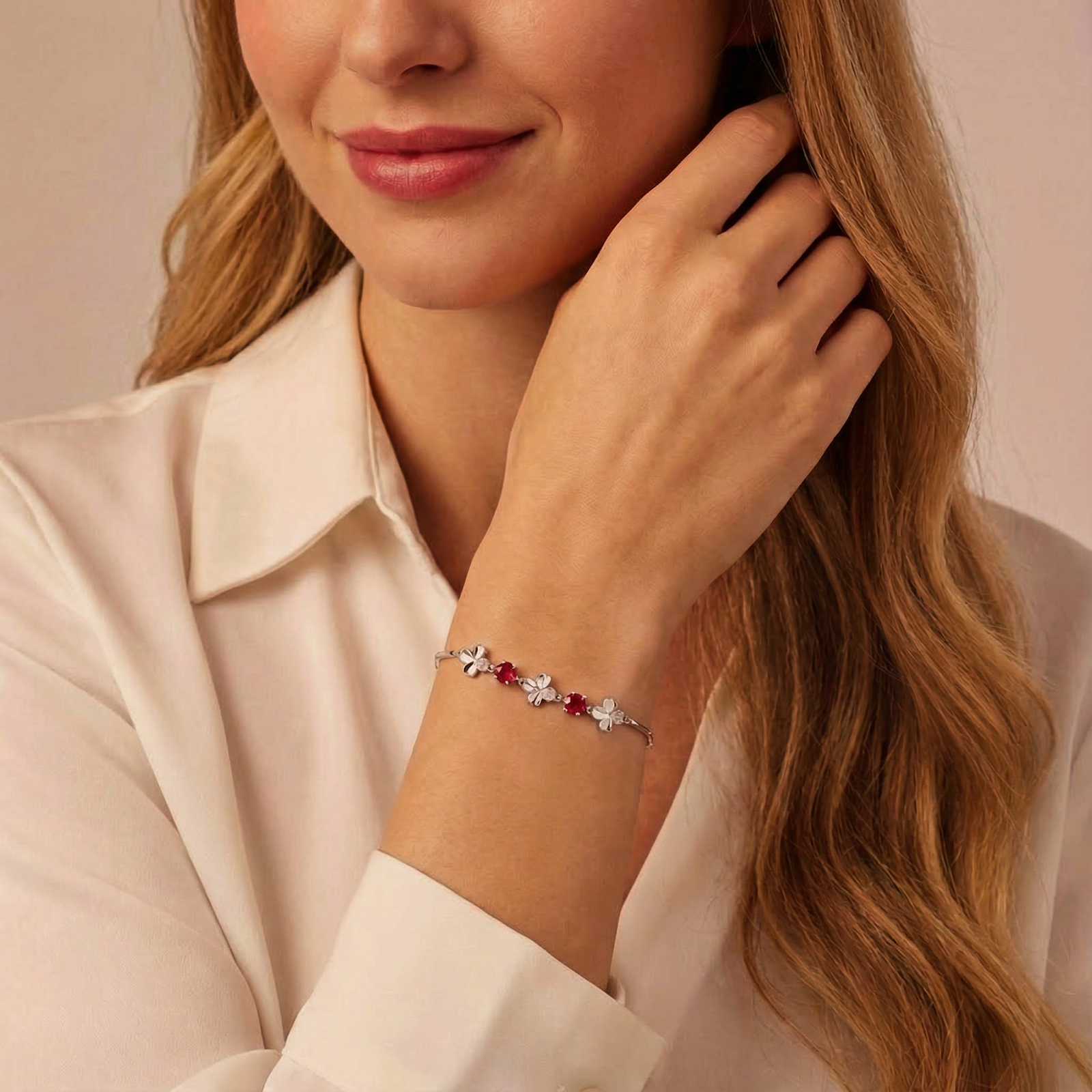 Model wearing the sterling silver clover bracelet with red simulated rubies on her wrist.