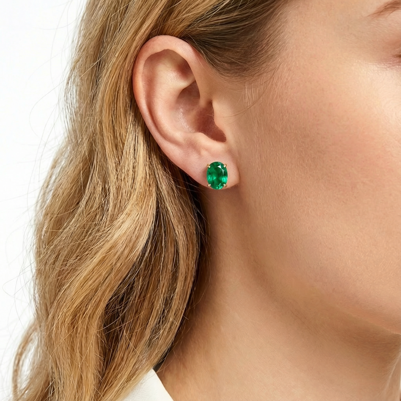 Woman wearing an Elianore oval simulated emerald stud earring in 18K gold vermeil.