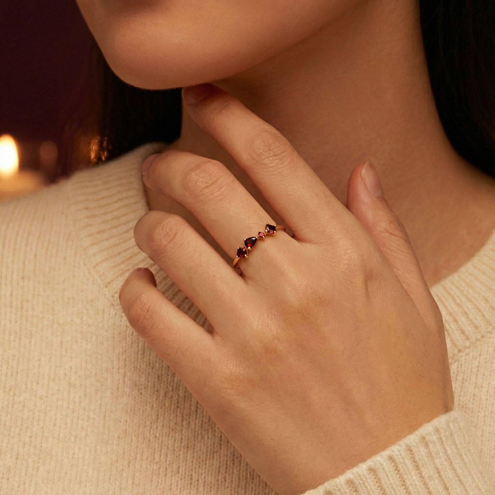 Model wearing the 18K gold vermeil Lunette ring with red simulated garnet stones on her finger with a cream sweater.
