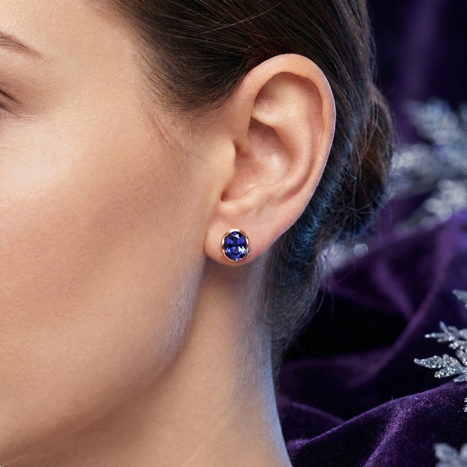 Woman wearing a Thalira oval simulated tanzanite stud earring in 18K gold vermeil.