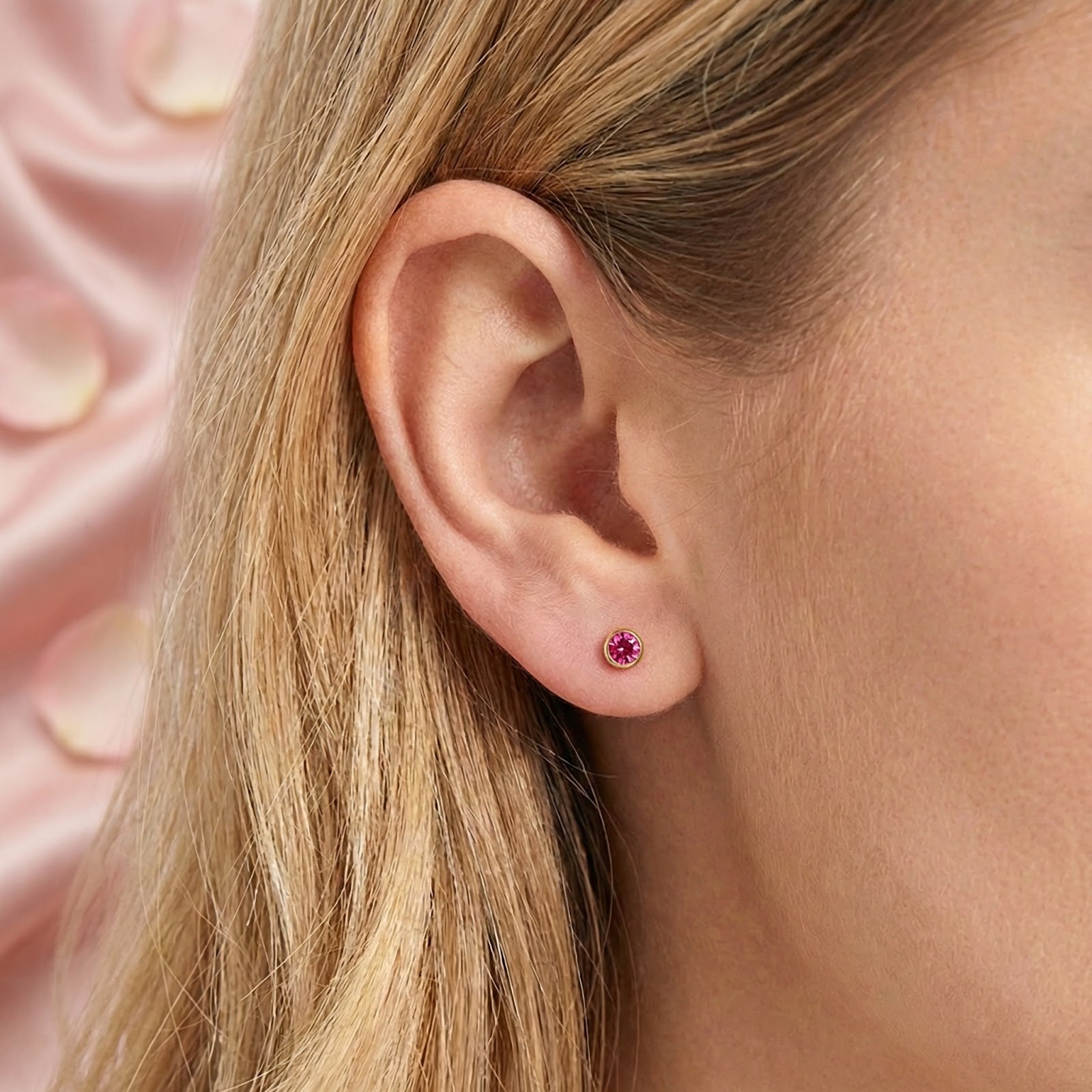 Close-up view of a Marisel pink tourmaline bezel stud earring in 18K gold vermeil worn on a model's ear.