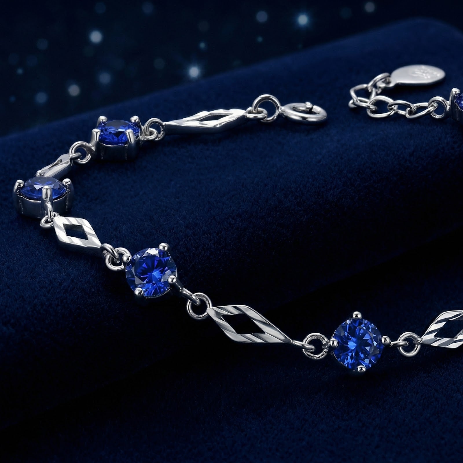 Macro view of round-cut blue sapphires and diamond-shaped silver links on the Nerienne station bracelet.