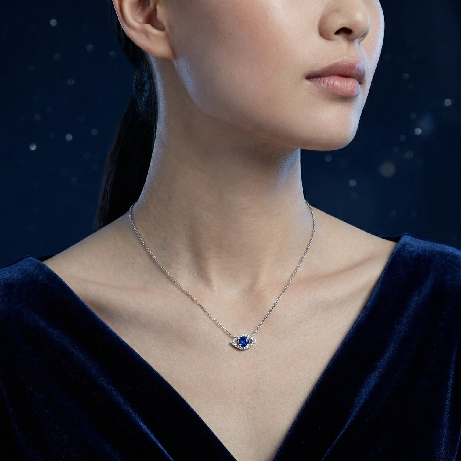 Sterling silver Syrenne Eye necklace with a round blue sapphire worn by a model in a dark blue dress.