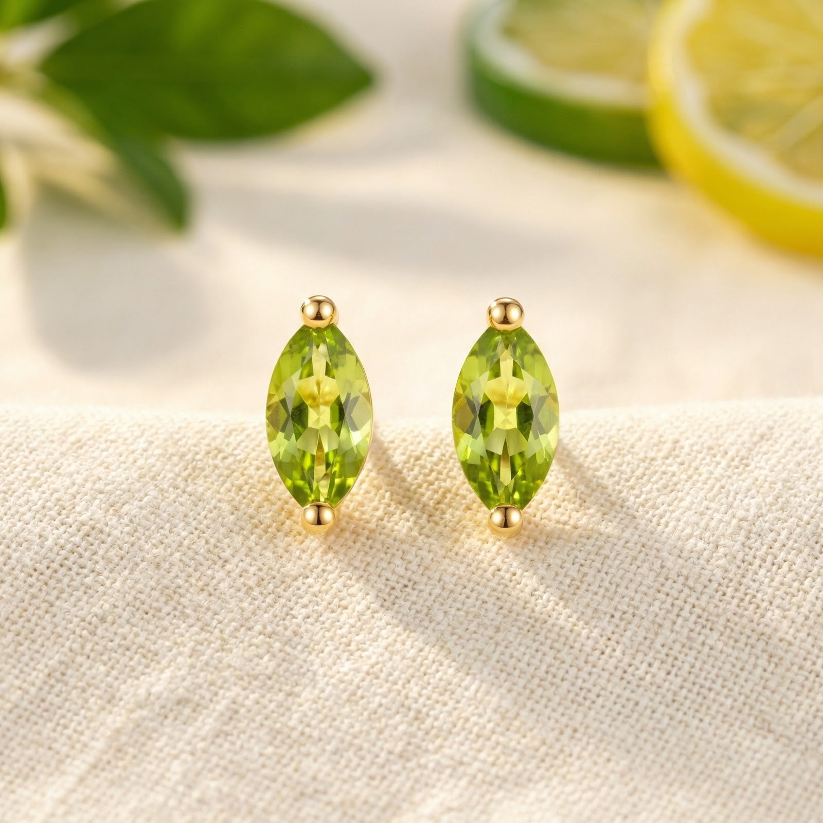 Front view of marquise-cut simulated peridot stud earrings in 18K gold vermeil on a textured surface.