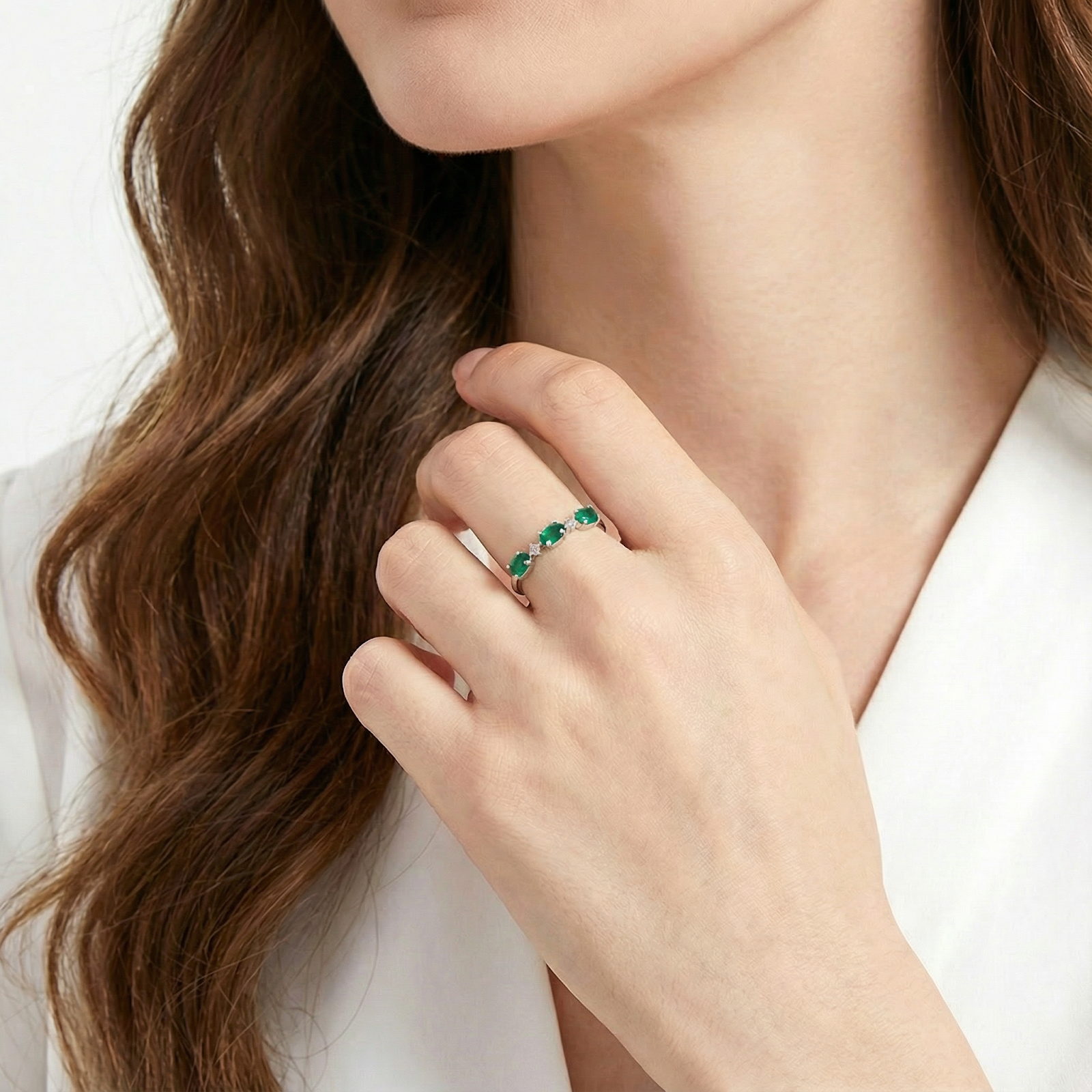 Model wearing the sterling silver bypass ring with three oval simulated emeralds, highlighting its scale on the finger.