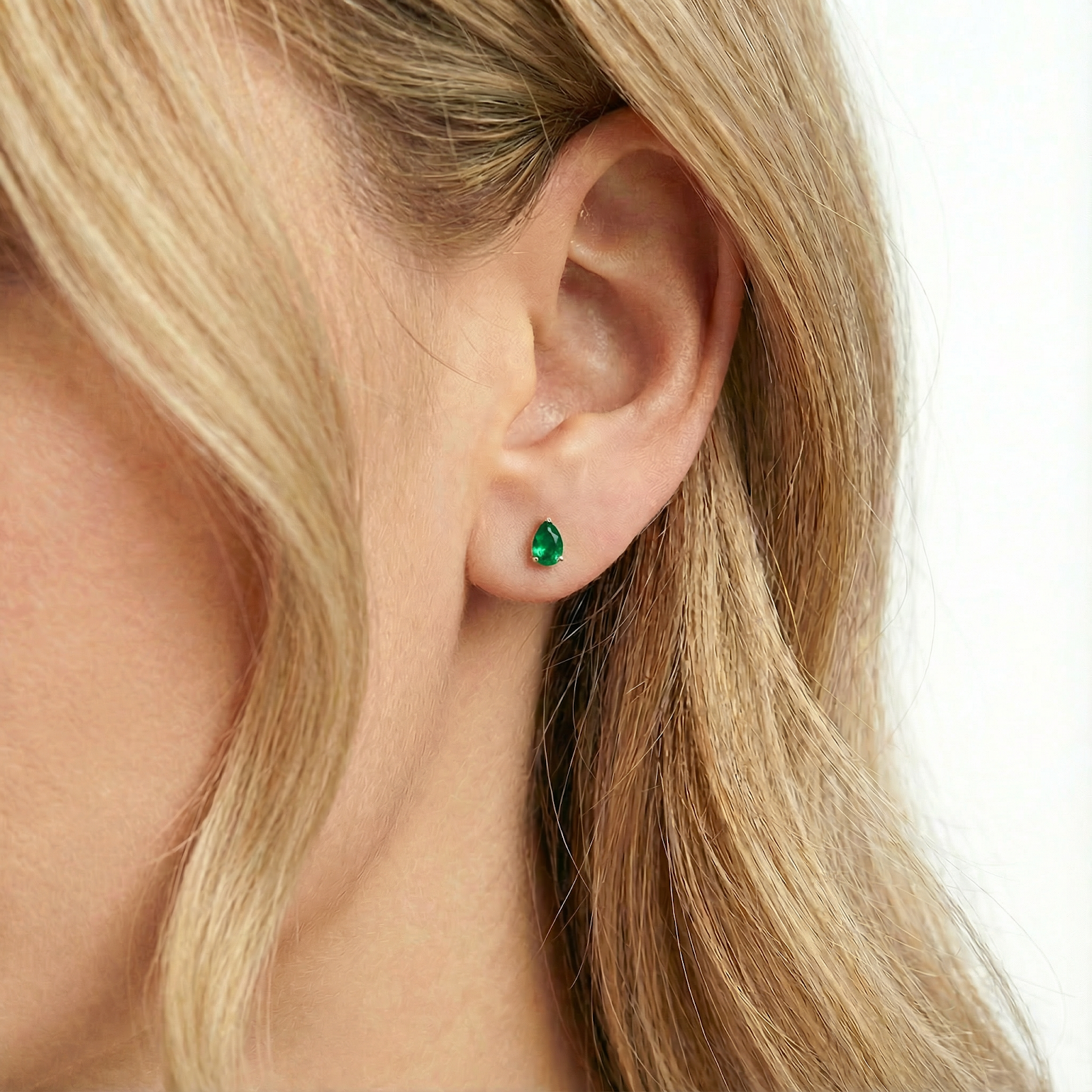 Side view of a model wearing the pear-cut simulated emerald earring in 18K gold vermeil.