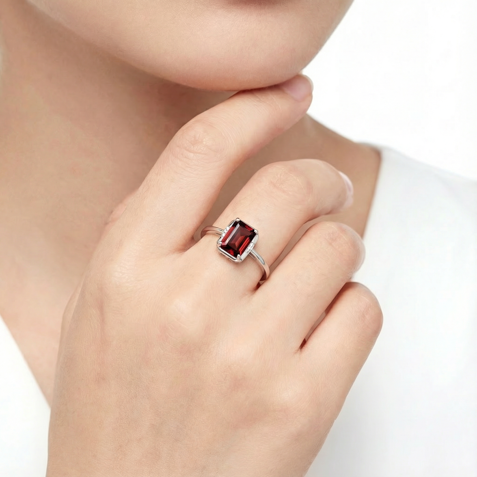 Emerald-cut simulated garnet ring in S925 sterling silver worn on a model's hand against a white background.
