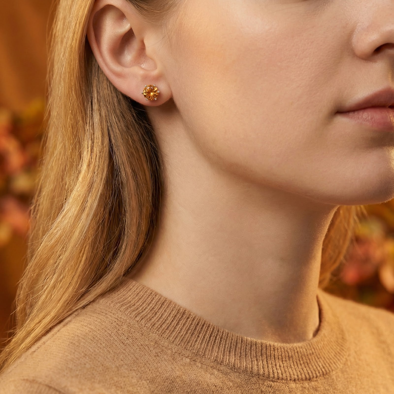 Woman wearing a round-cut simulated topaz stud earring in sterling silver.