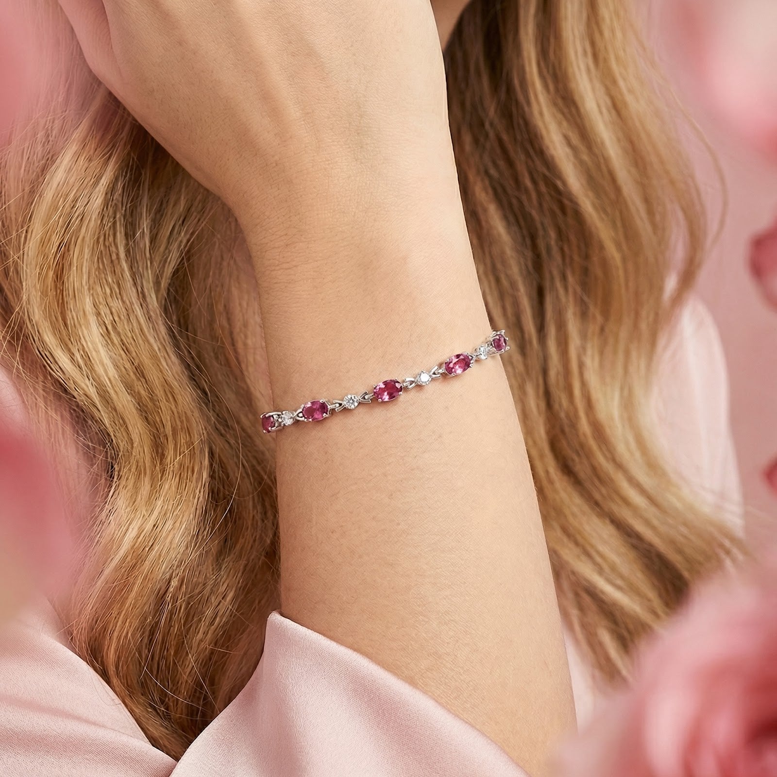 Woman wearing the Evantelle oval simulated pink tourmaline bracelet in sterling silver on her wrist.