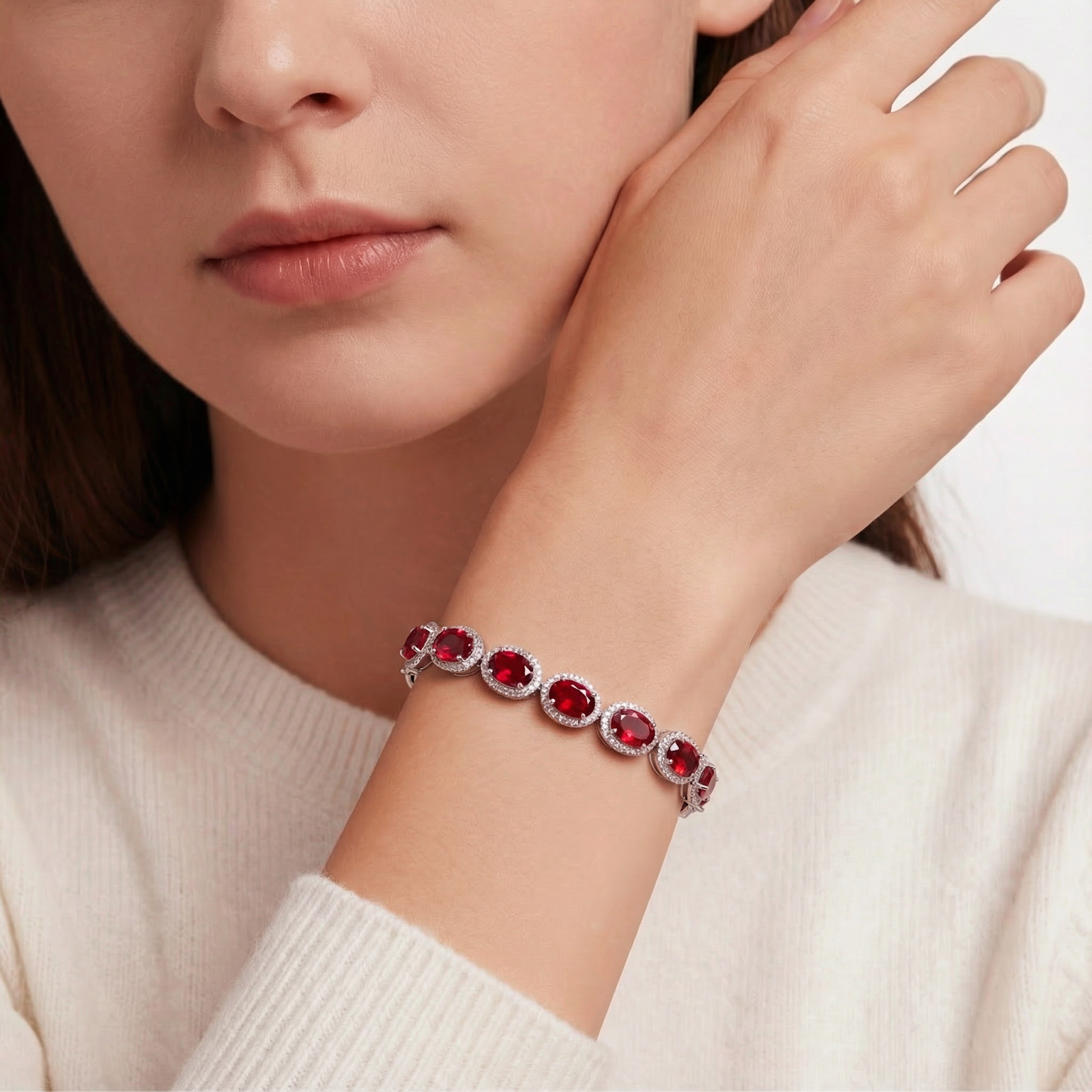 Model wearing the Bellara oval simulated ruby tennis bracelet in sterling silver on her wrist.