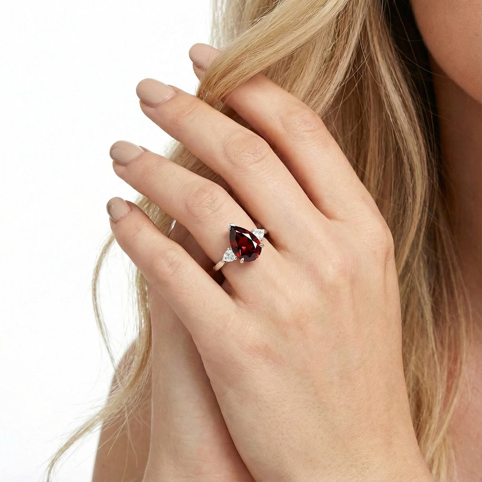 Close-up of a pear-shaped red garnet sterling silver ring worn on a hand, showing its brilliance.