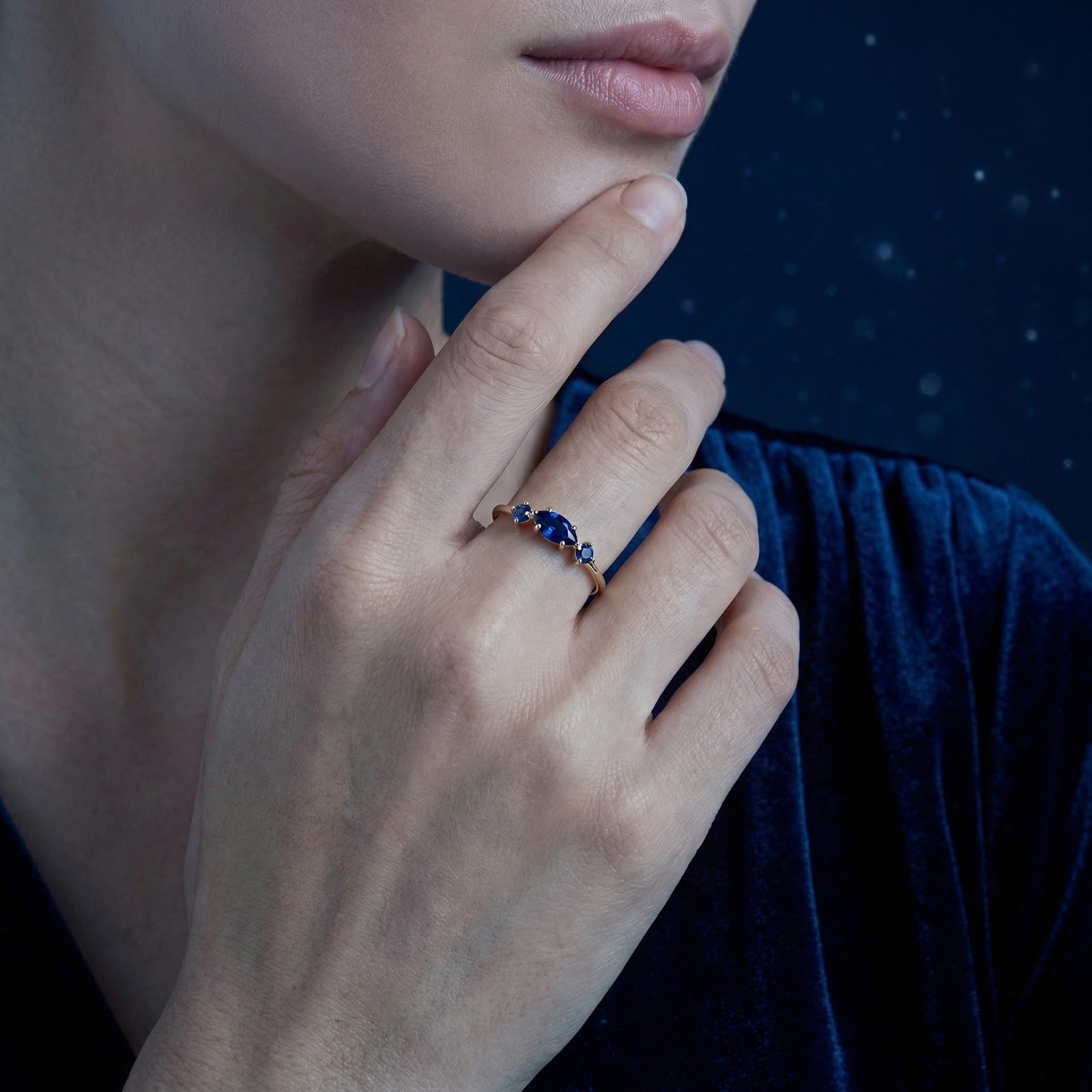 Model wearing a marquise cut simulated blue sapphire ring in 18K gold vermeil on her ring finger.