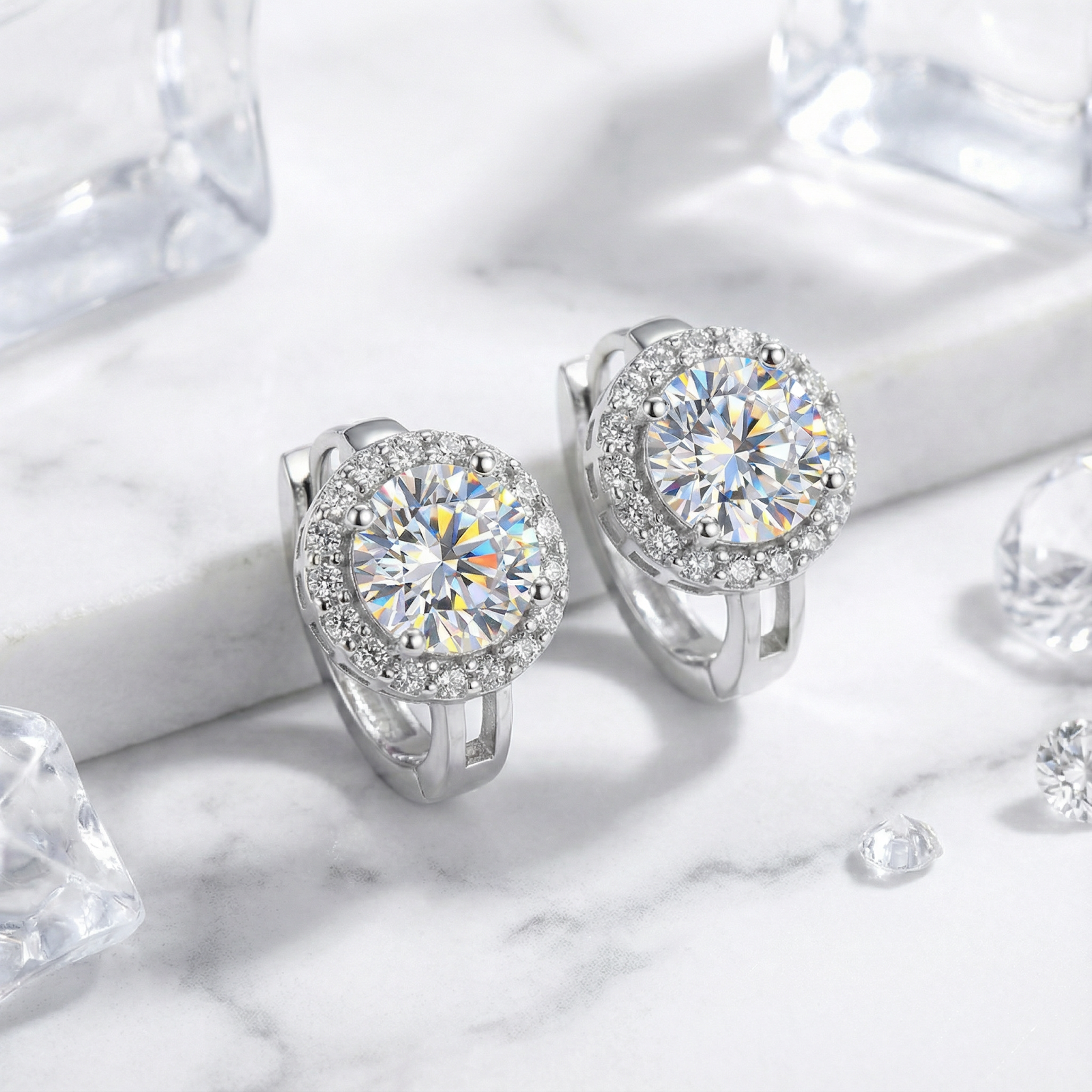 Sterling silver halo earrings with round cut 1CT moissanite stones showing rainbow fire on a marble surface.