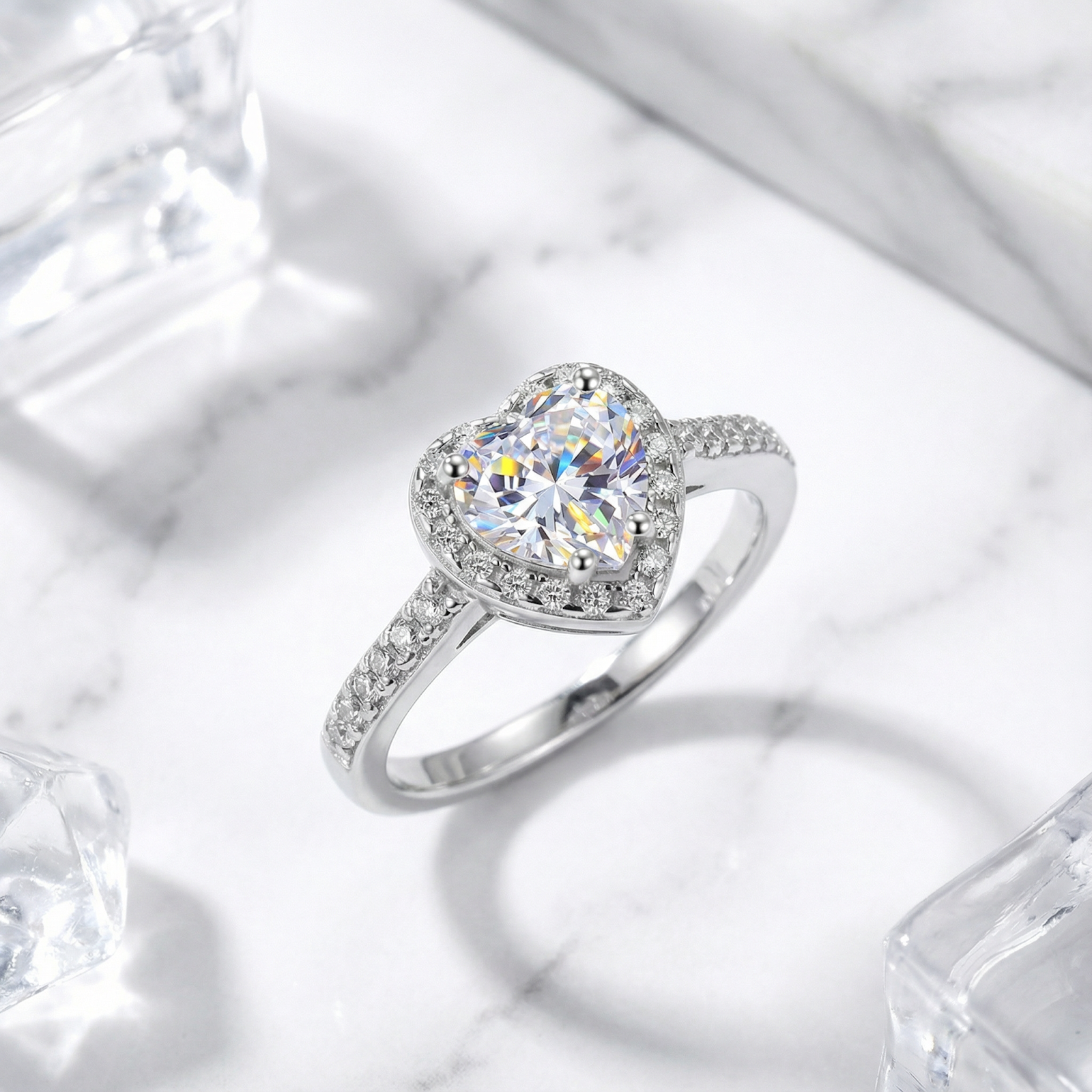 Heart-shaped simulated diamond halo ring in S925 sterling silver on a marble surface with ice cubes.