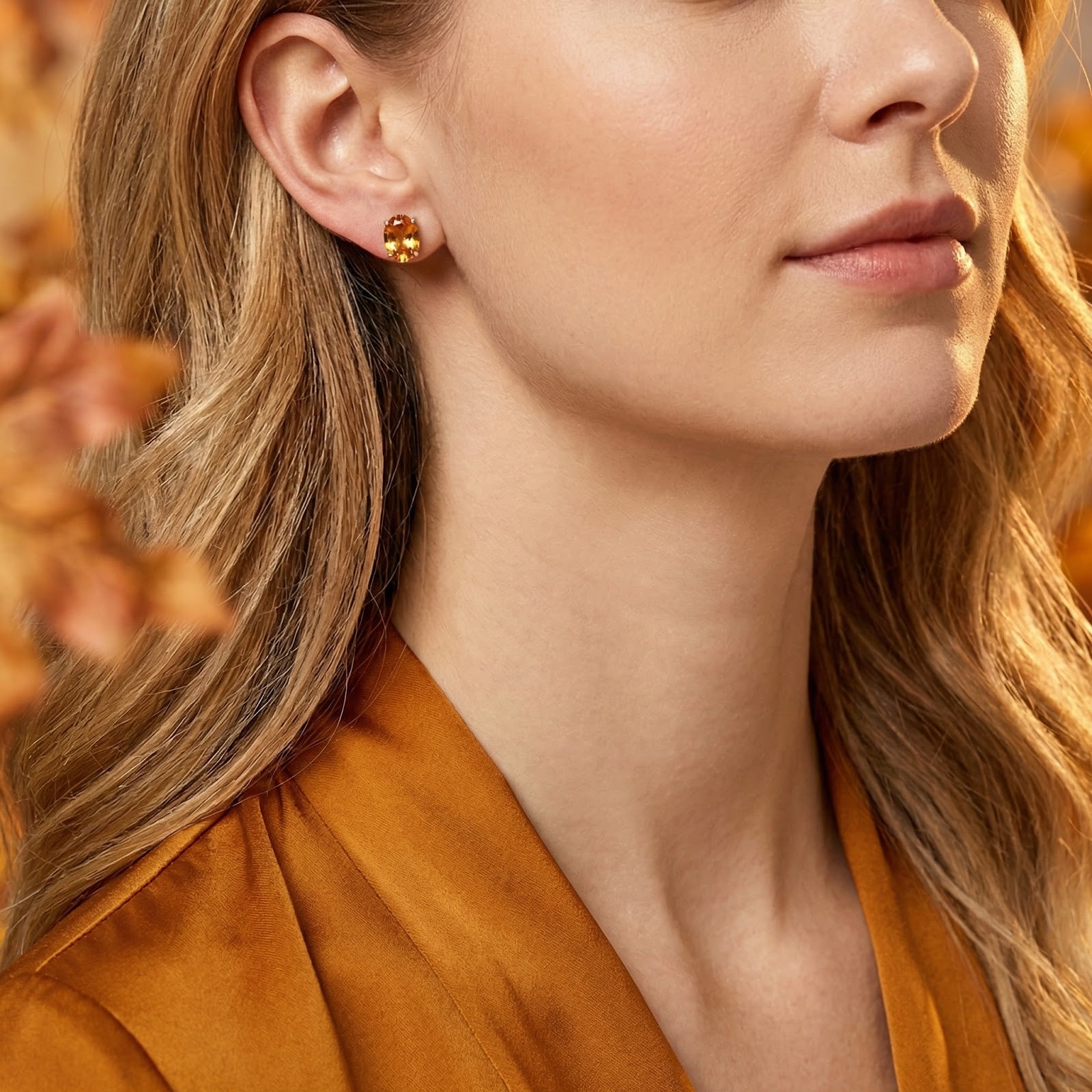 Woman wearing a honey-colored oval simulated topaz stud earring in a silver setting.