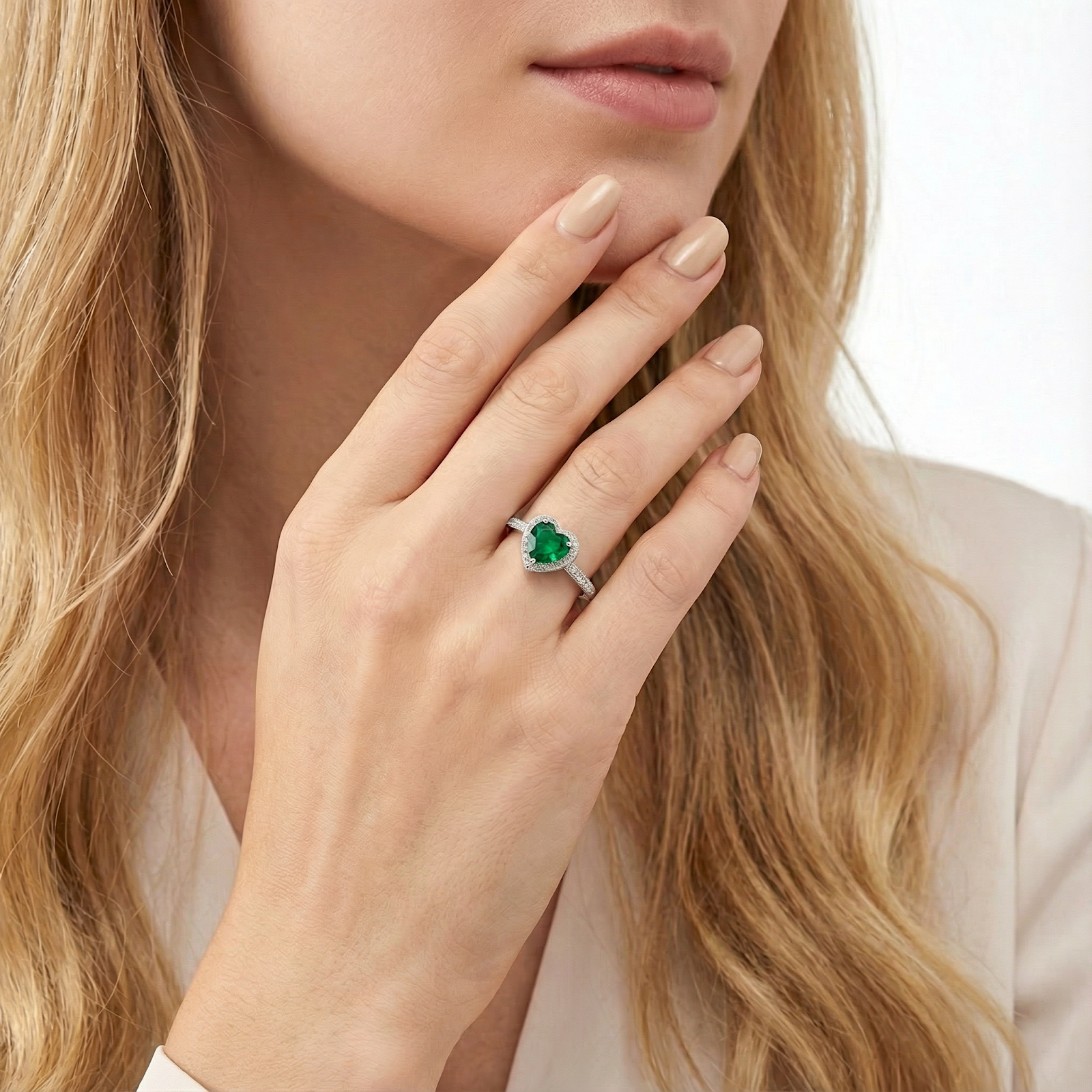 Heart-shaped simulated emerald ring in sterling silver worn on a woman's hand.