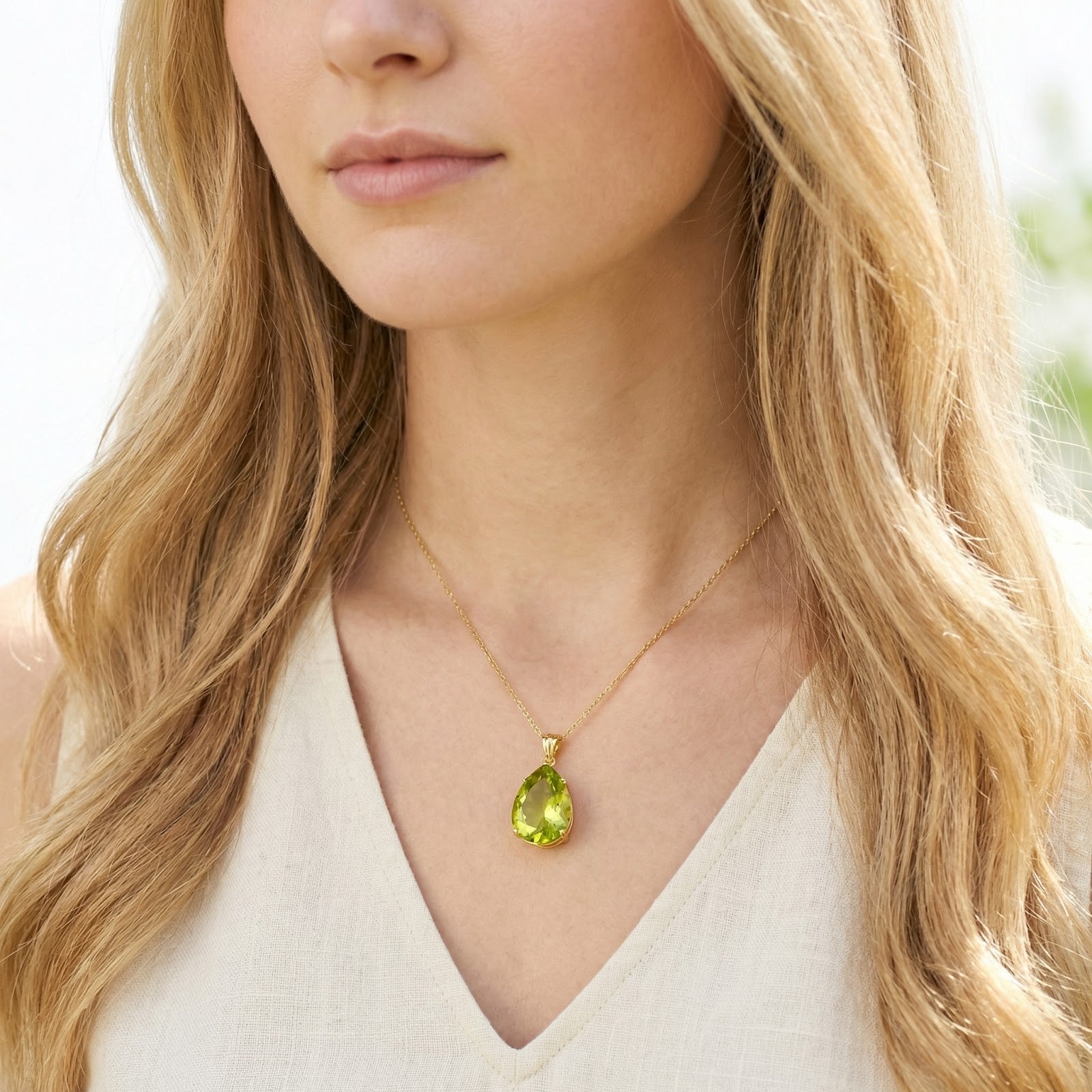Teardrop simulated peridot necklace in 18K gold vermeil worn by a blonde model in a white top.