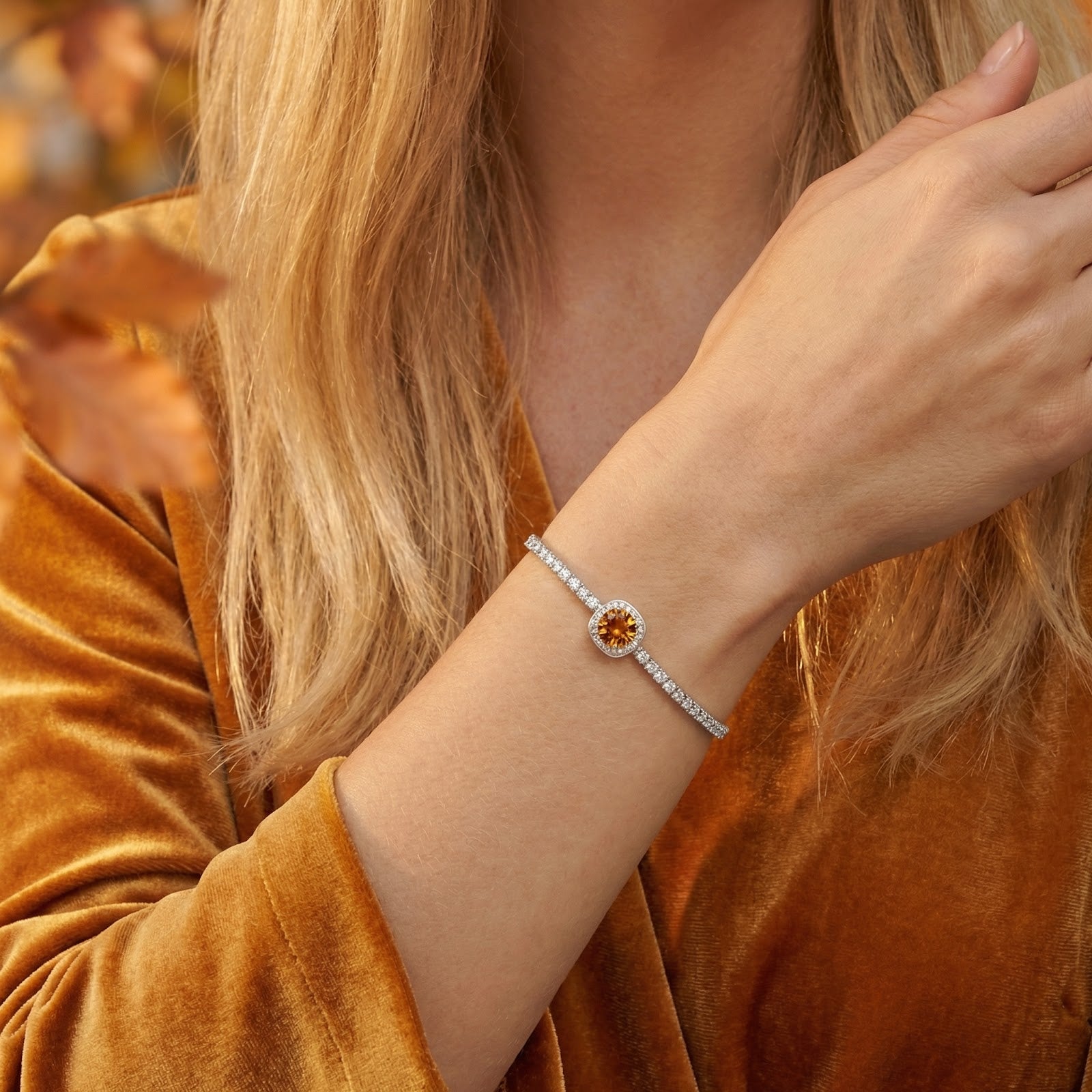 A woman wearing the adjustable sterling silver Luceria halo bracelet with a vibrant golden-orange topaz.
