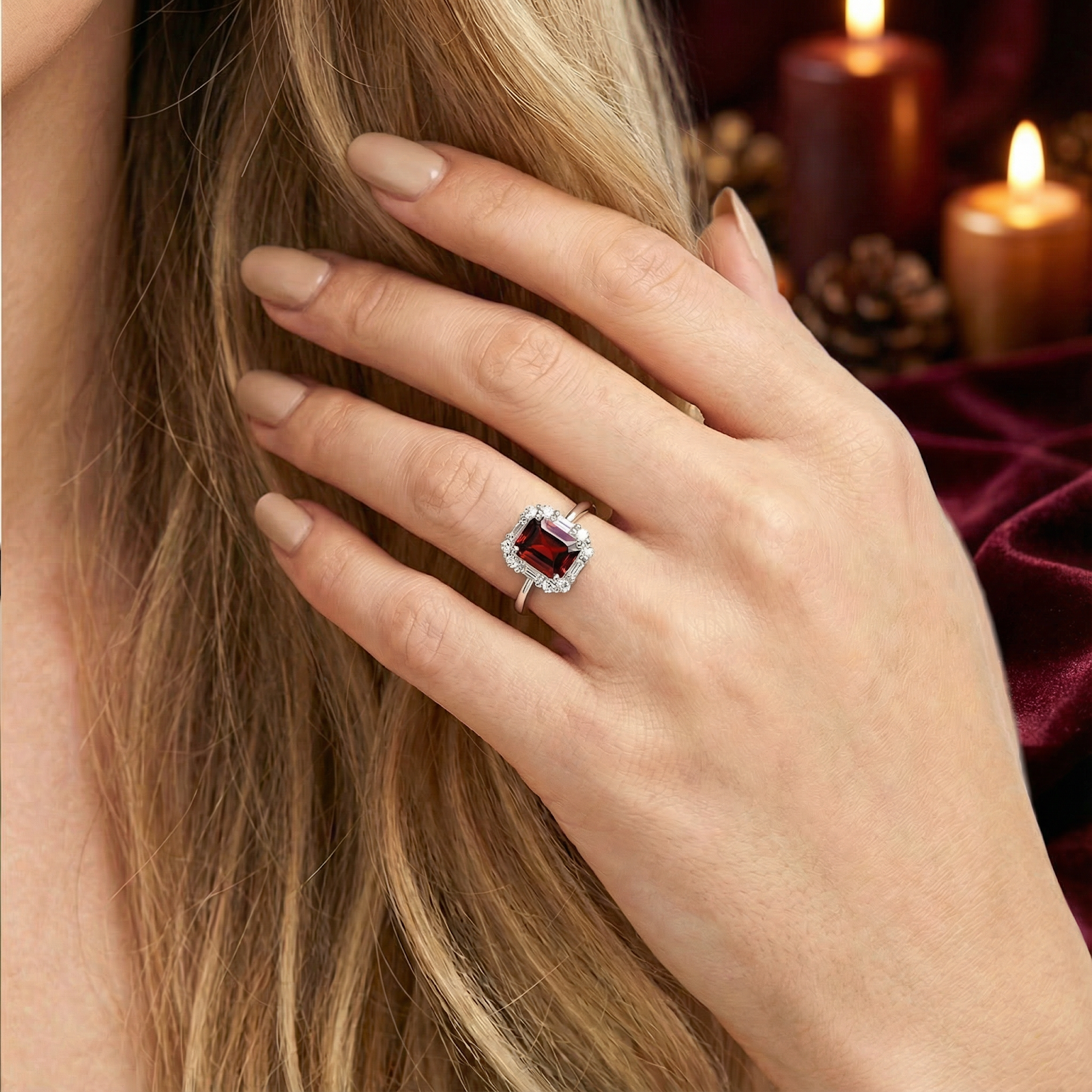Model wearing the octagon cut red garnet halo ring in sterling silver against a festive background.