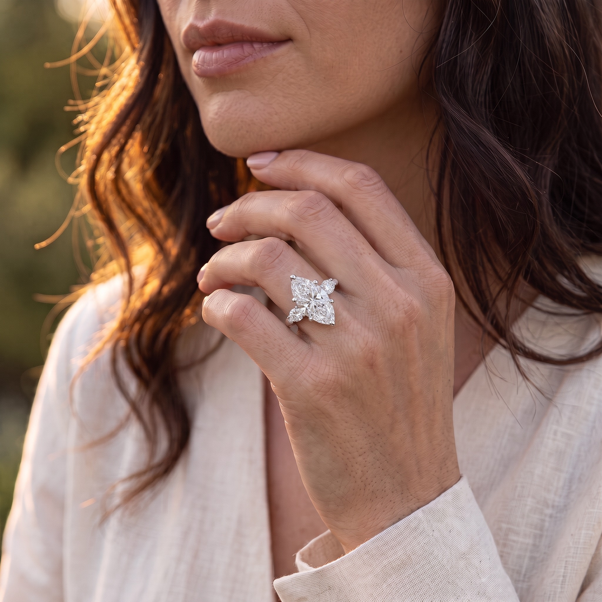 Silver marquise-cut moissanite ring worn on a model's hand near her chin.