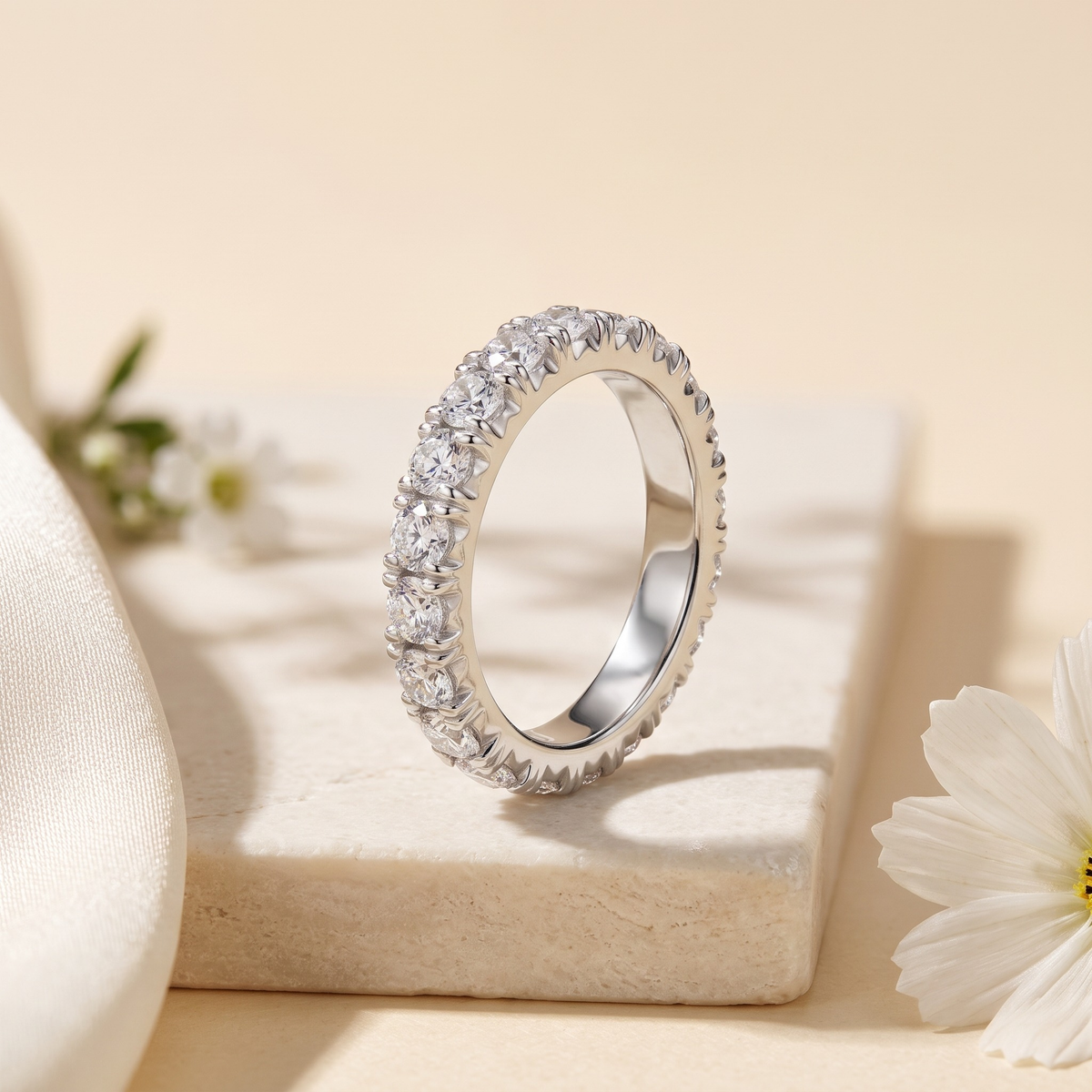 Round moissanite eternity band in silver, upright product view.