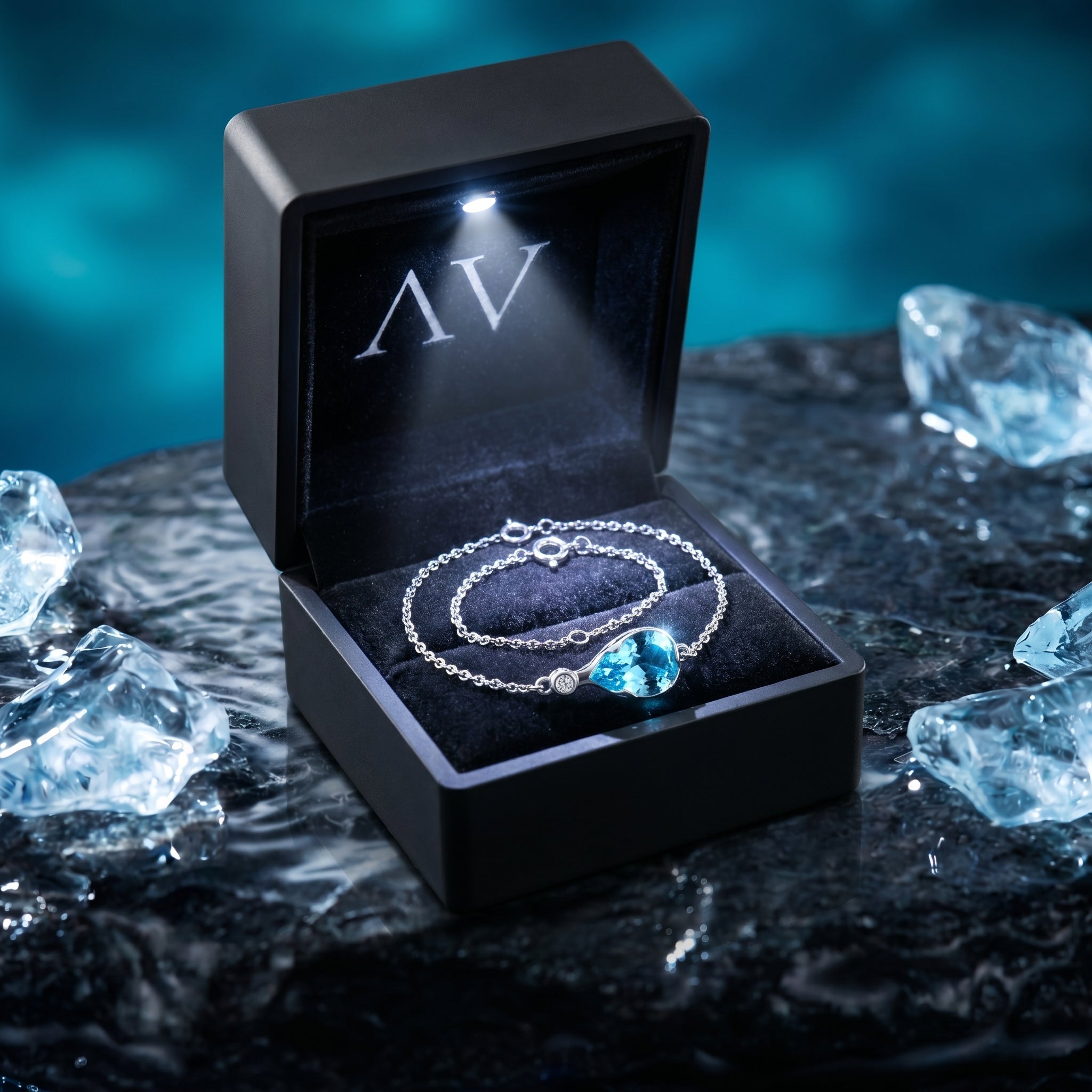 Pear cut aquamarine platinum bracelet inside a black lighted jewelry box on a dark stone.