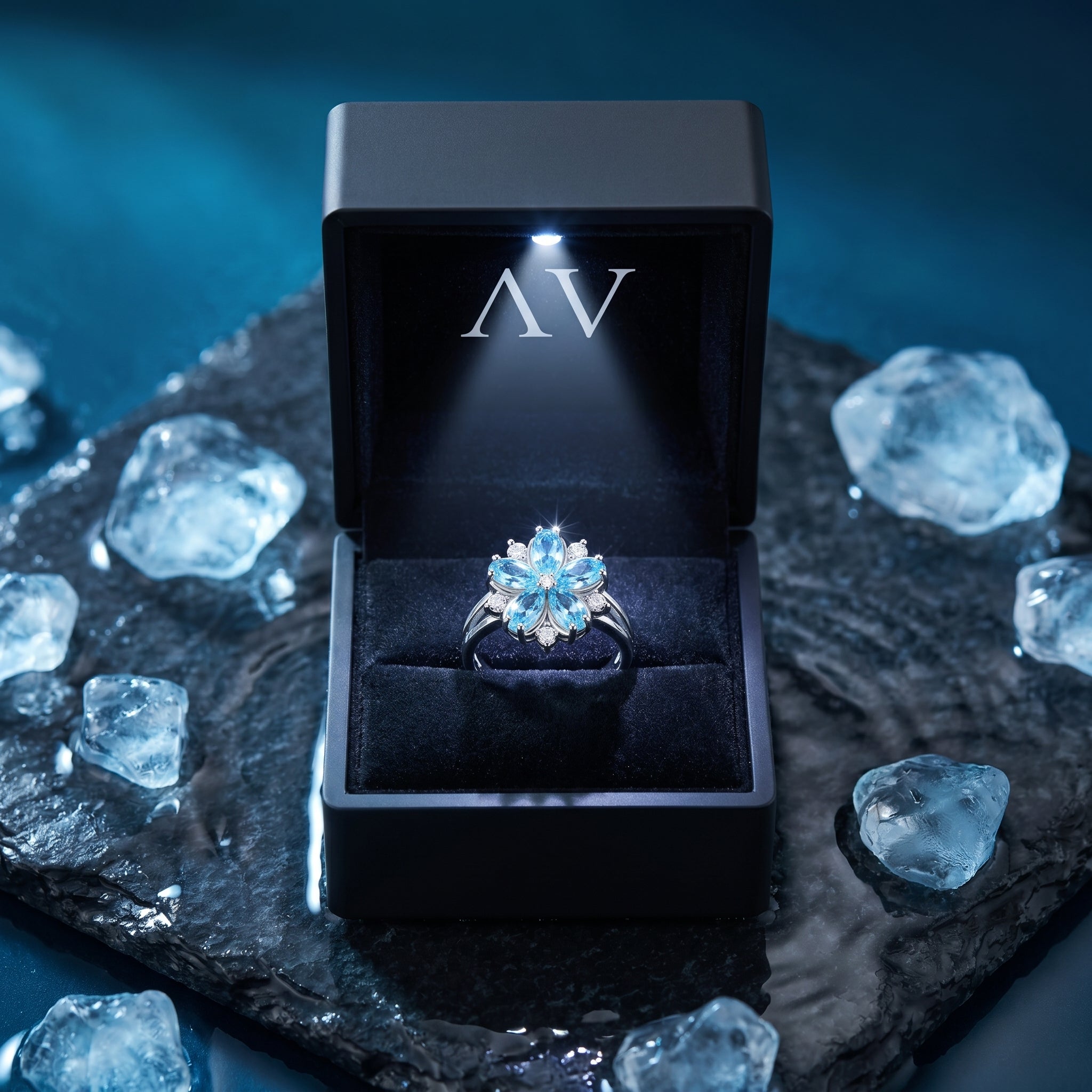 Aquamarine floral ring presented in a black lighted gift box on a dark stone surface with ice accents.