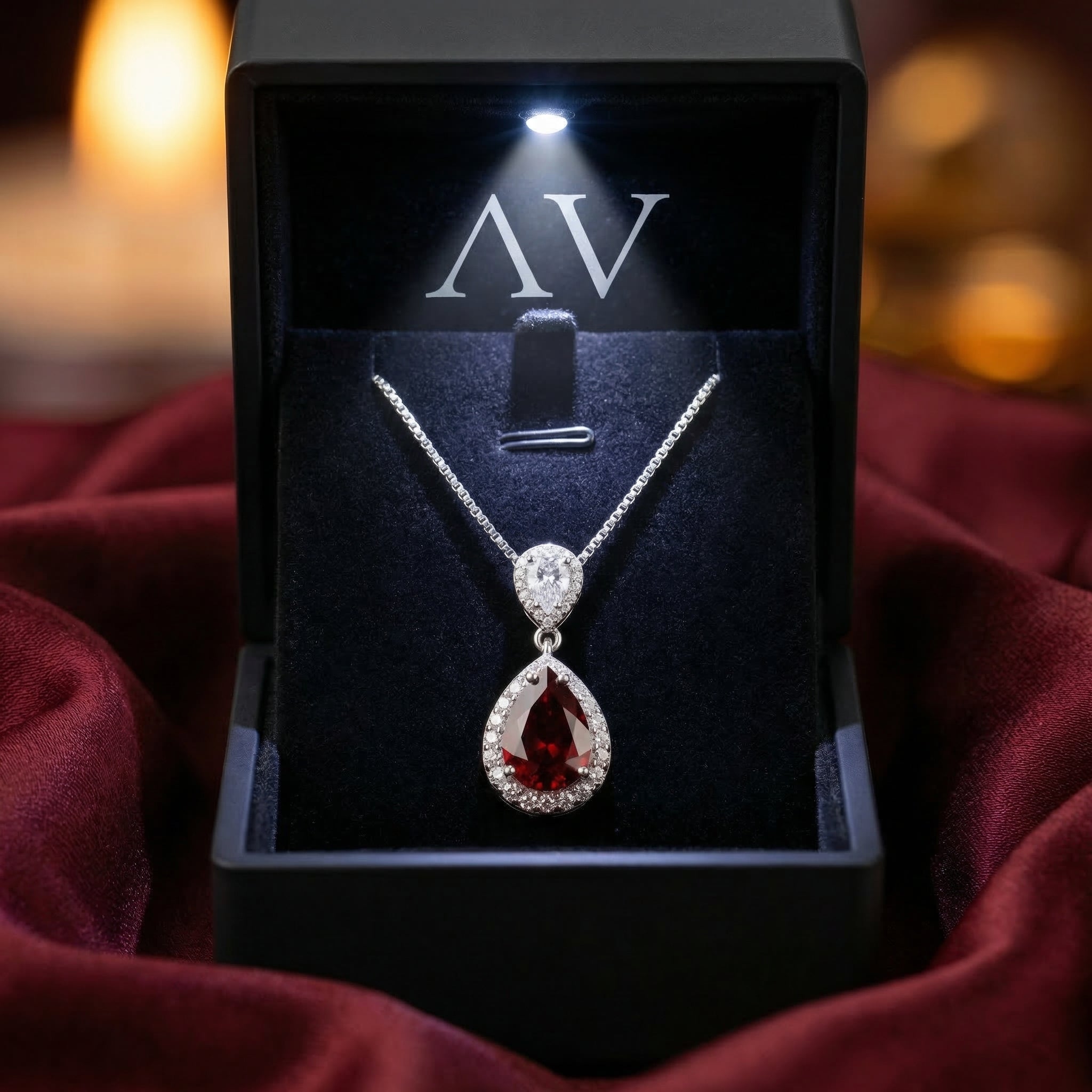 Silver pear cut garnet necklace presented in a premium black lighted jewelry box on red fabric.