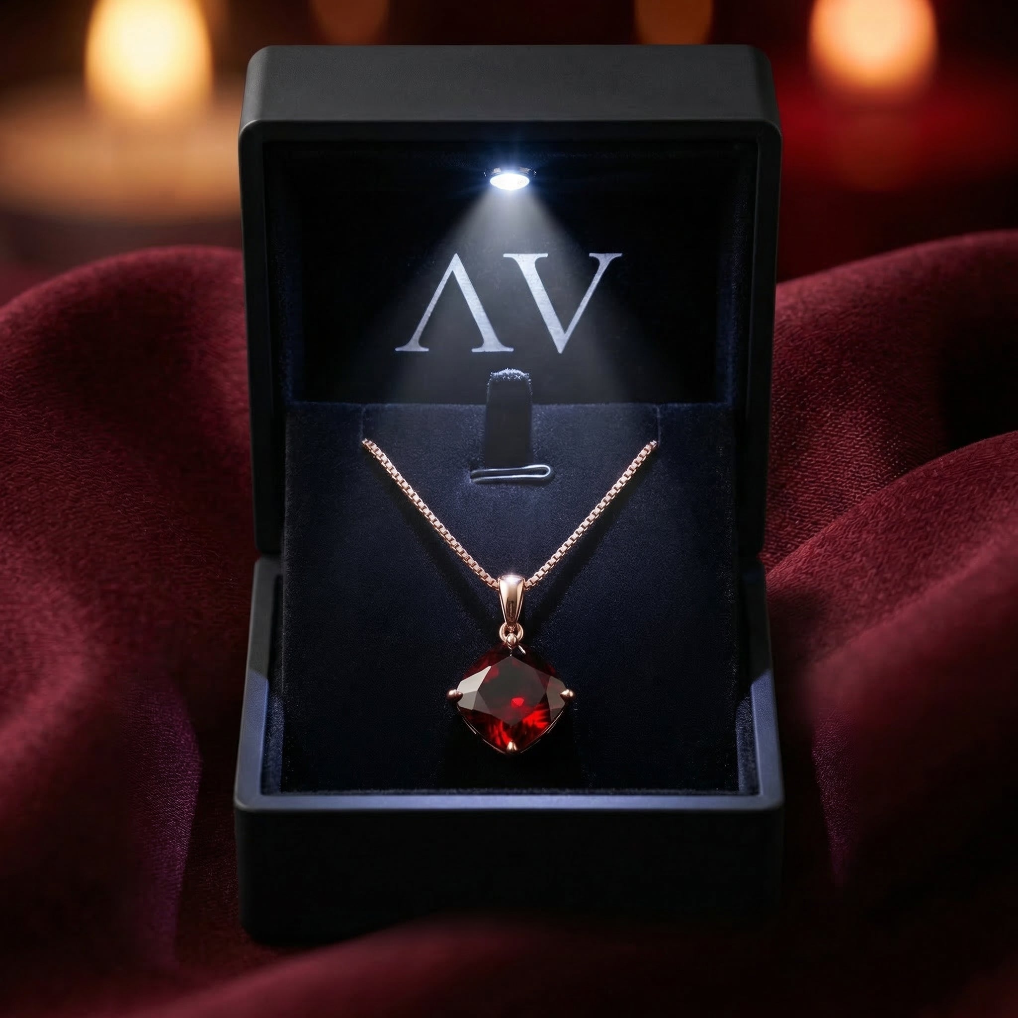 The 18K rose gold garnet necklace displayed inside a premium black LED-lit jewelry gift box on red silk.