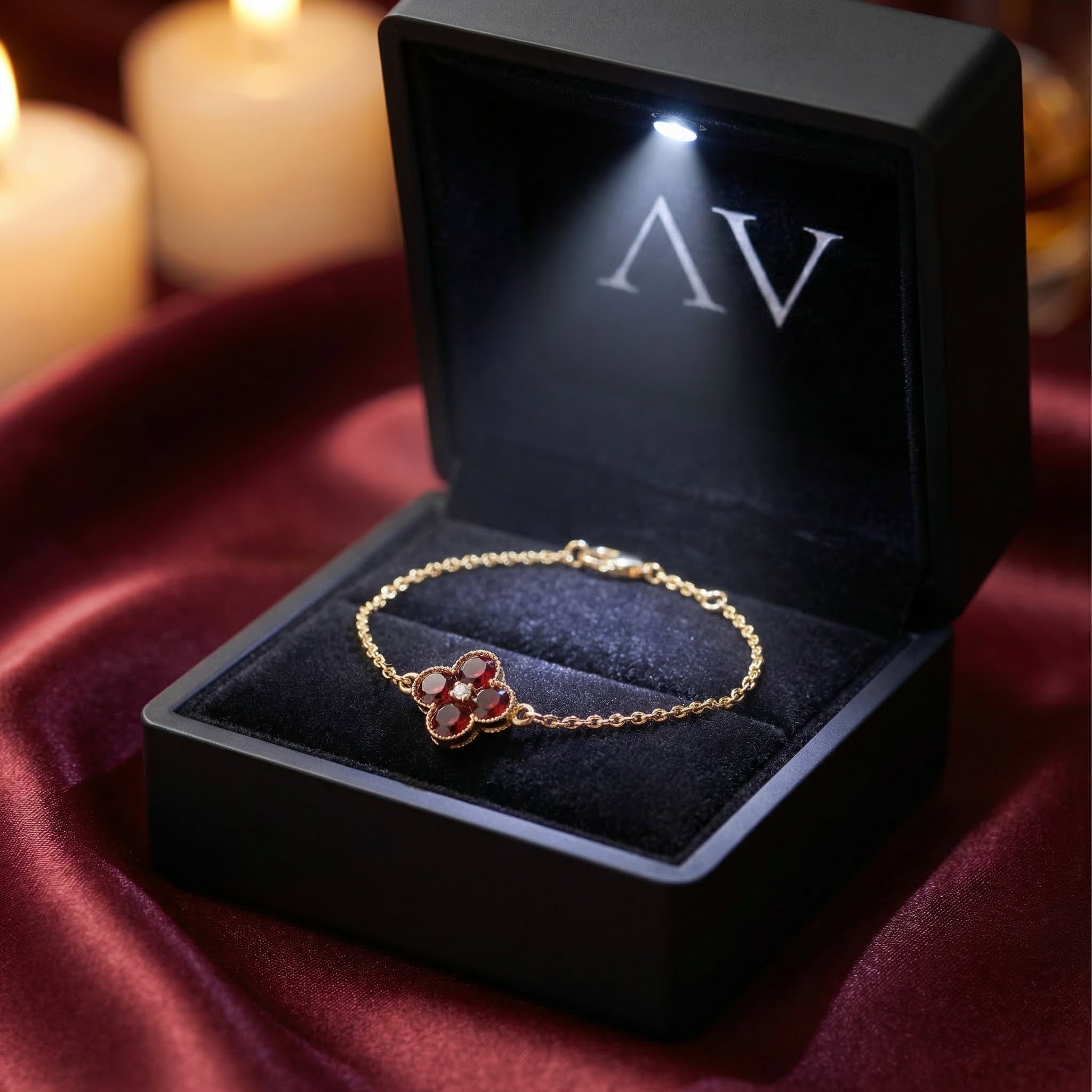 18K yellow gold garnet station bracelet presented in a lighted black jewelry box on red silk.