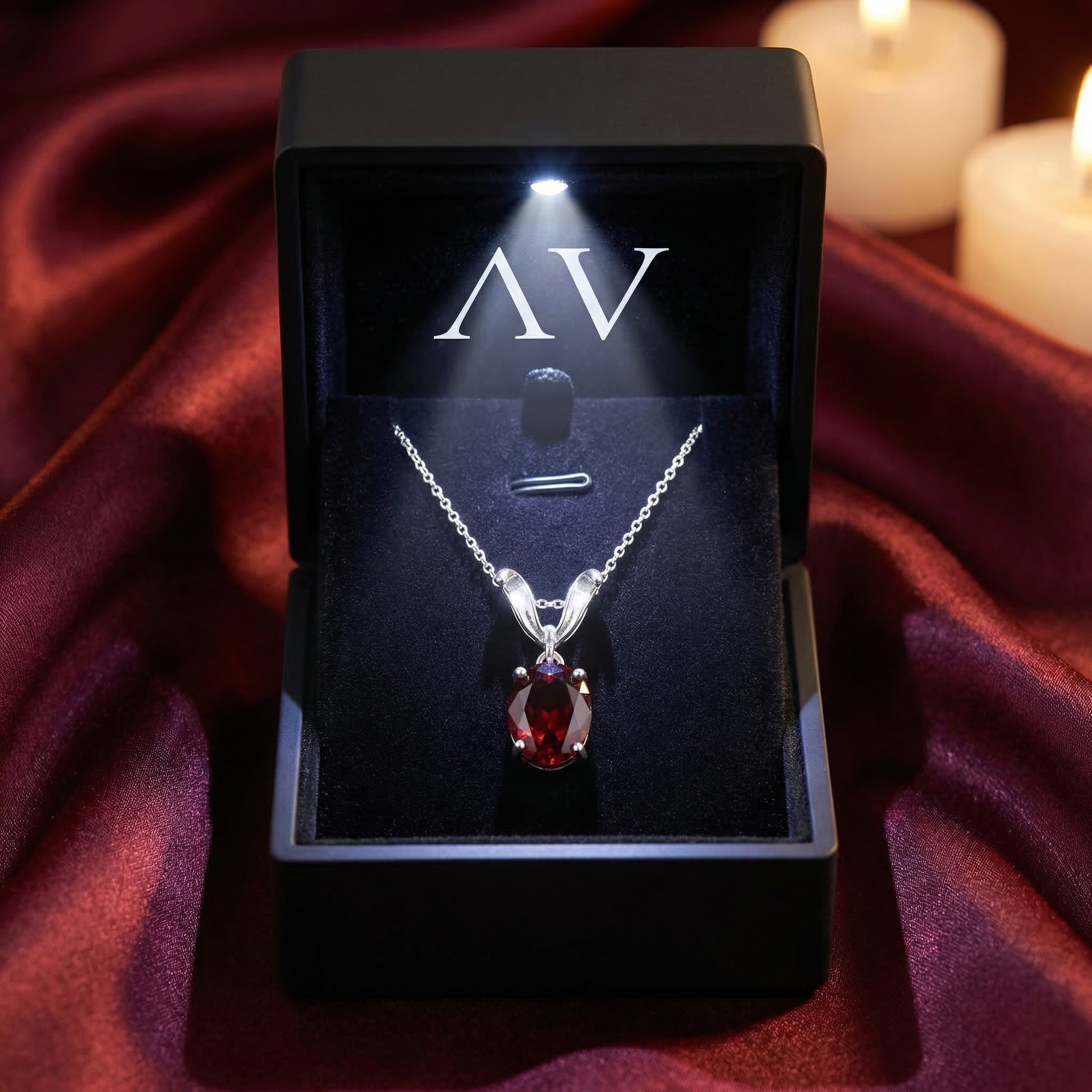 Natural oval garnet silver necklace displayed in a black LED-lighted gift box on red fabric.