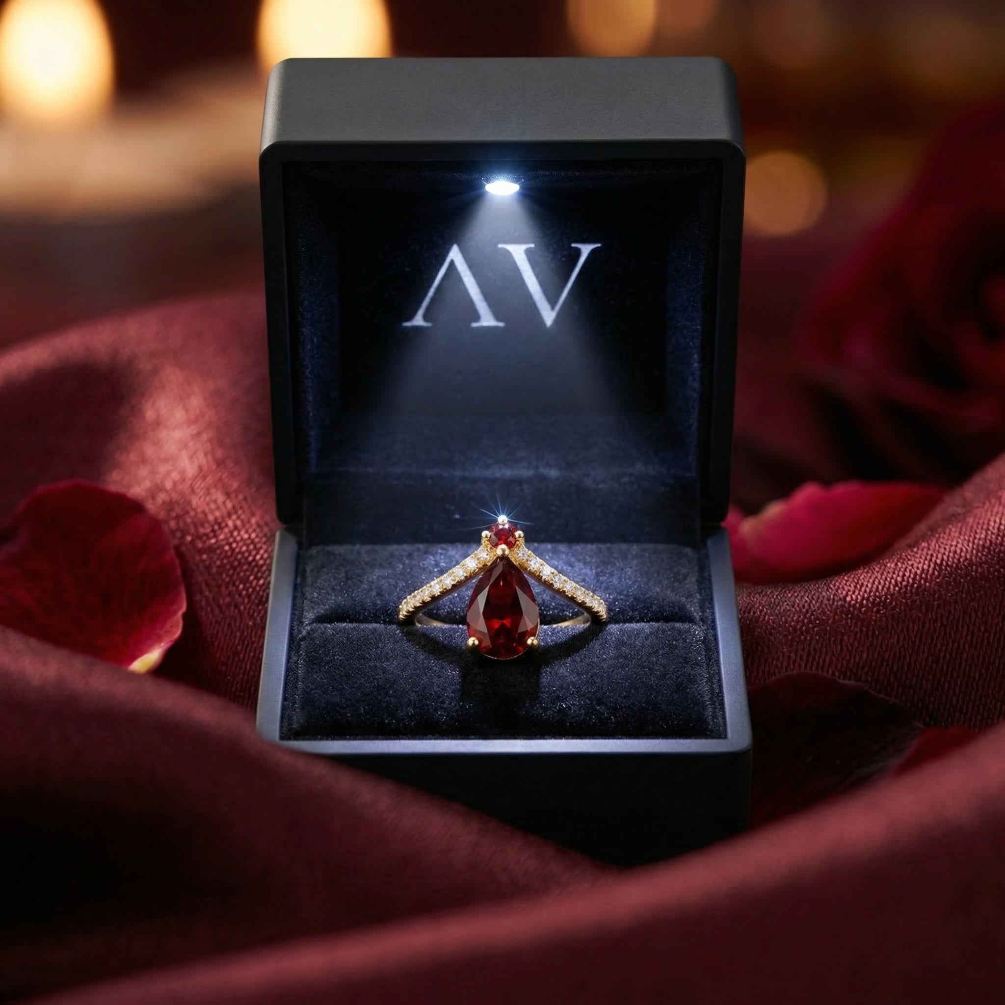 Pear-cut garnet chevron ring in 18K gold vermeil inside a black LED-lit presentation box with AV branding.