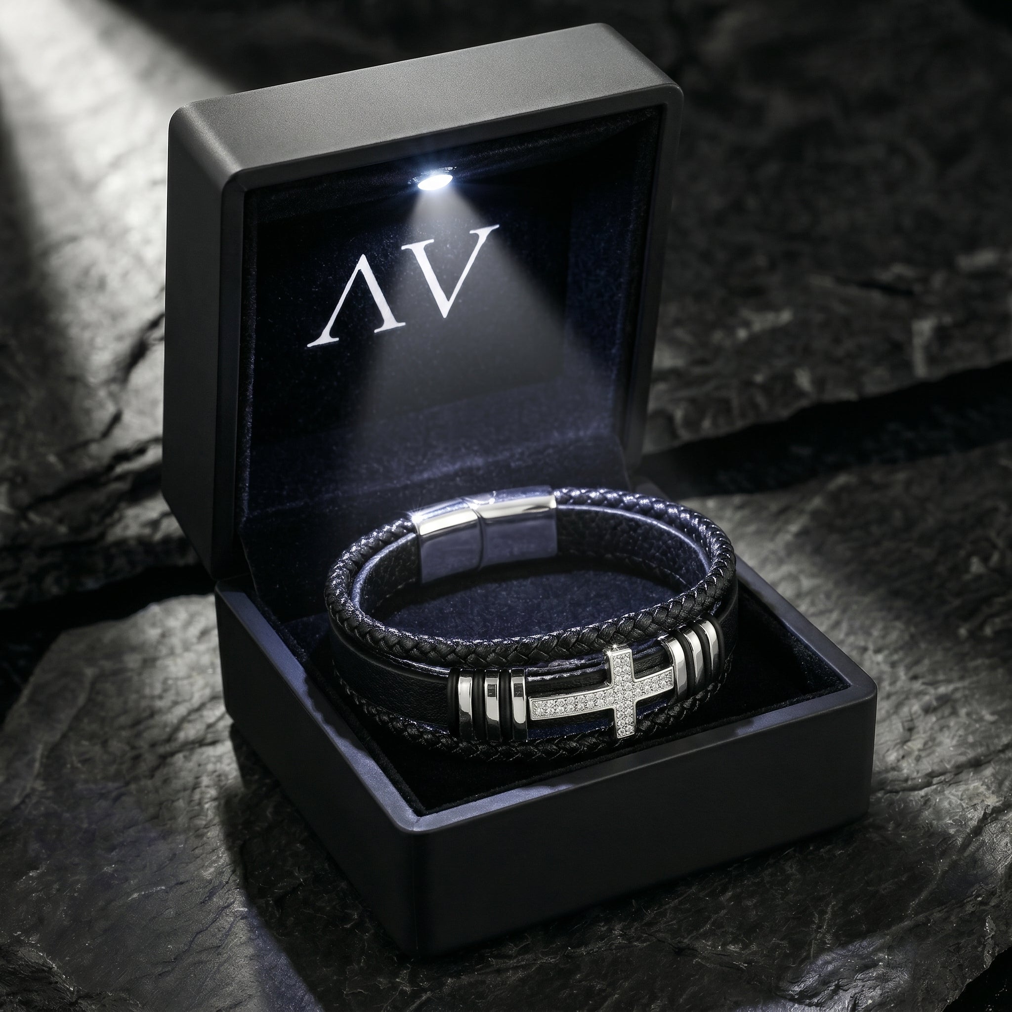 Aegis Cross Bracelet presented in a premium black LED-lit gift box with AV branding on a stone surface.