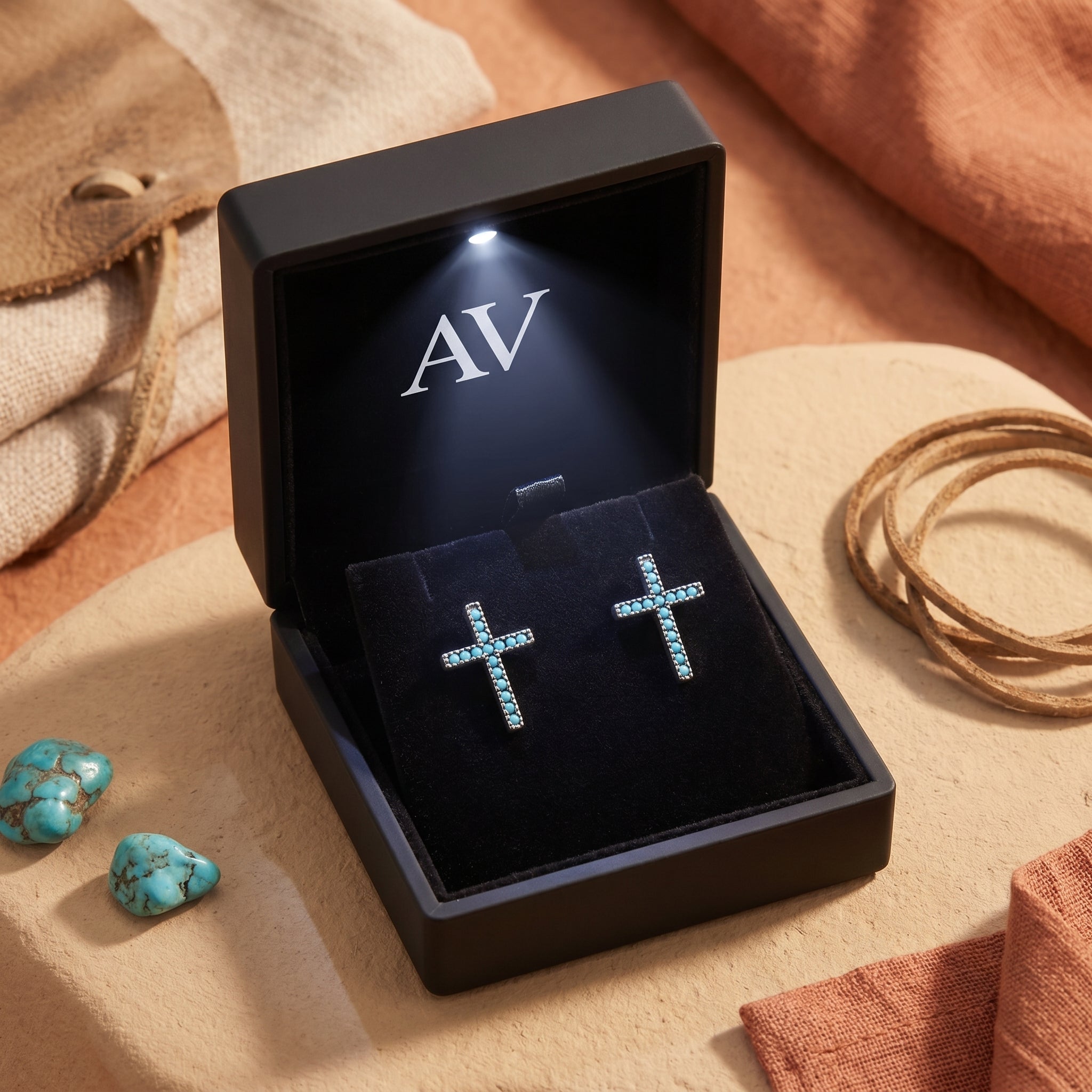 Turquoise cross earrings displayed in a premium black LED-lit gift box with the AV logo.