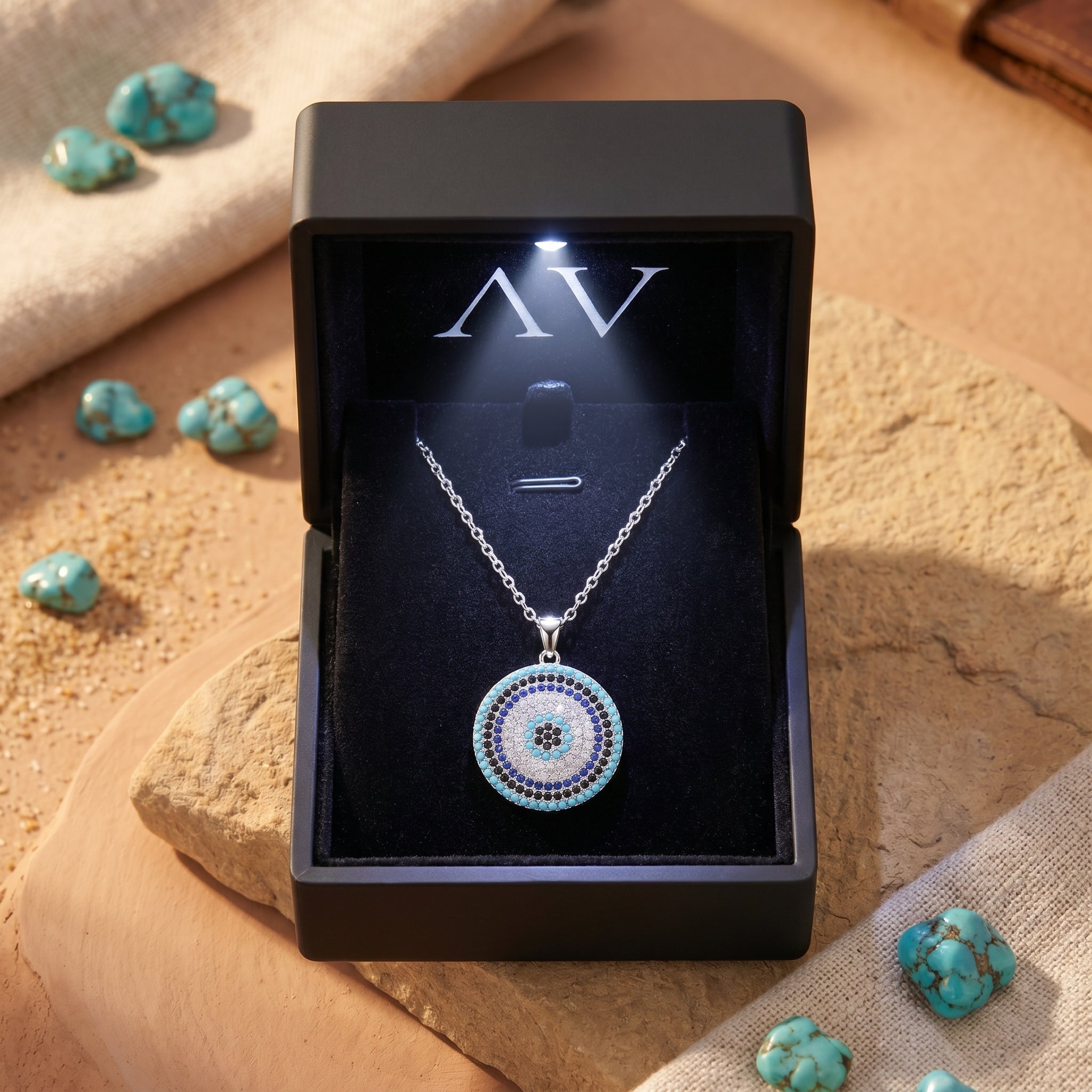 Silver Cielo turquoise pendant necklace inside a black LED-lit jewelry box on a desert-themed background.