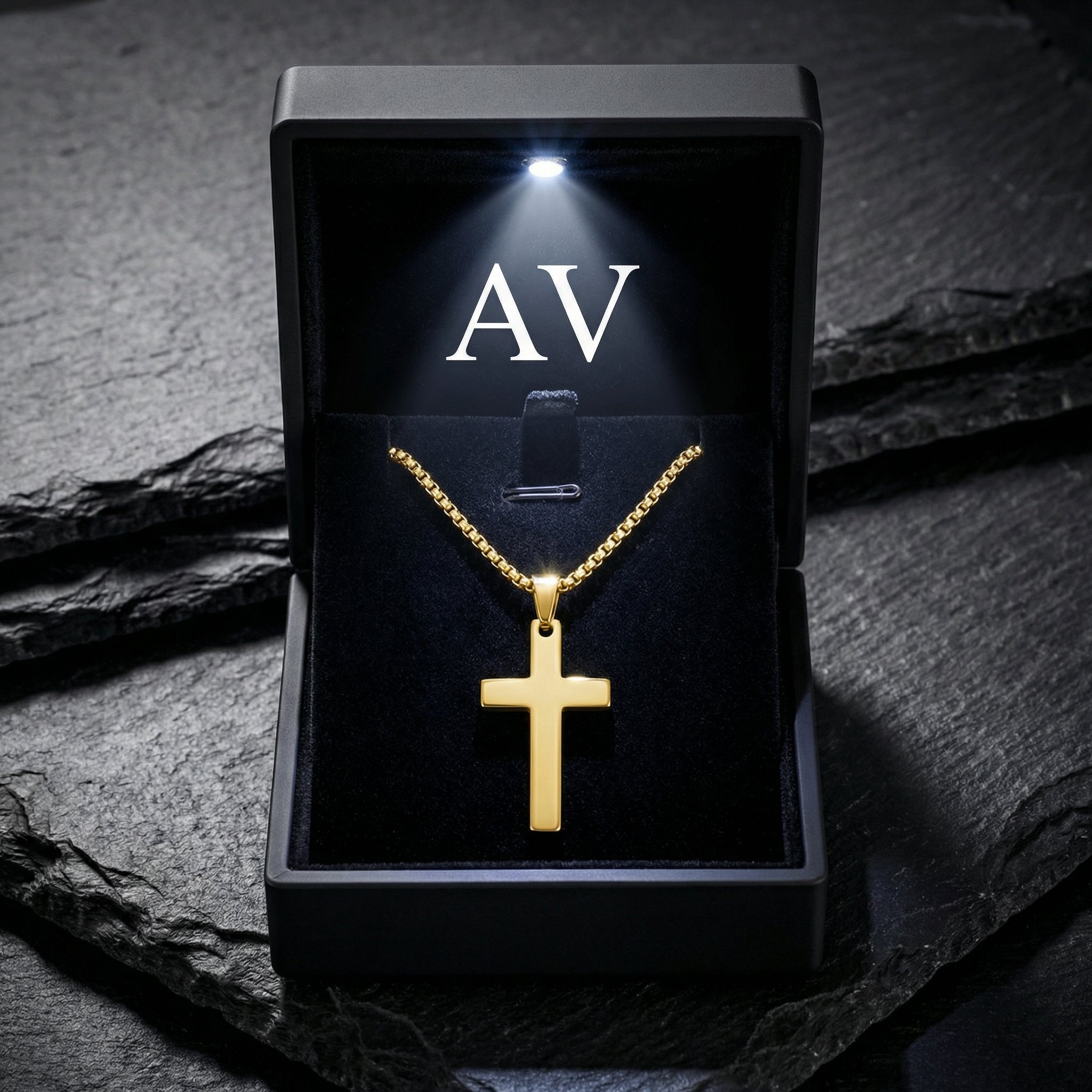 Gold Apostle Cross pendant displayed in a premium black LED-lit gift box on a textured surface.