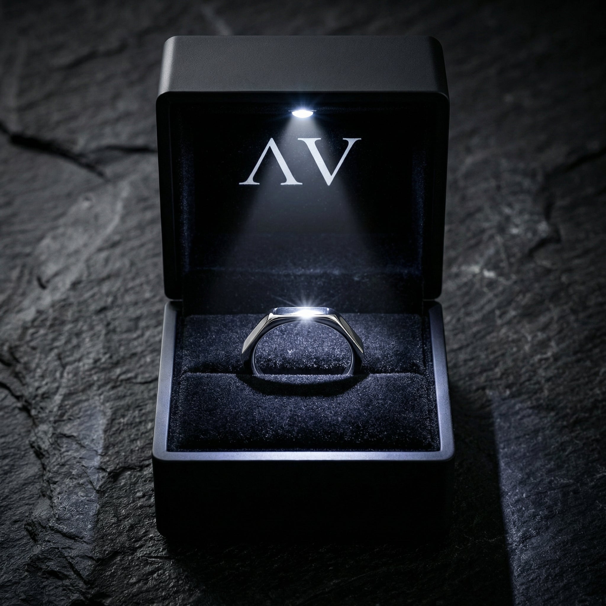 Silver Spartan signet ring presented in a premium black LED-lit jewelry box on a stone surface.
