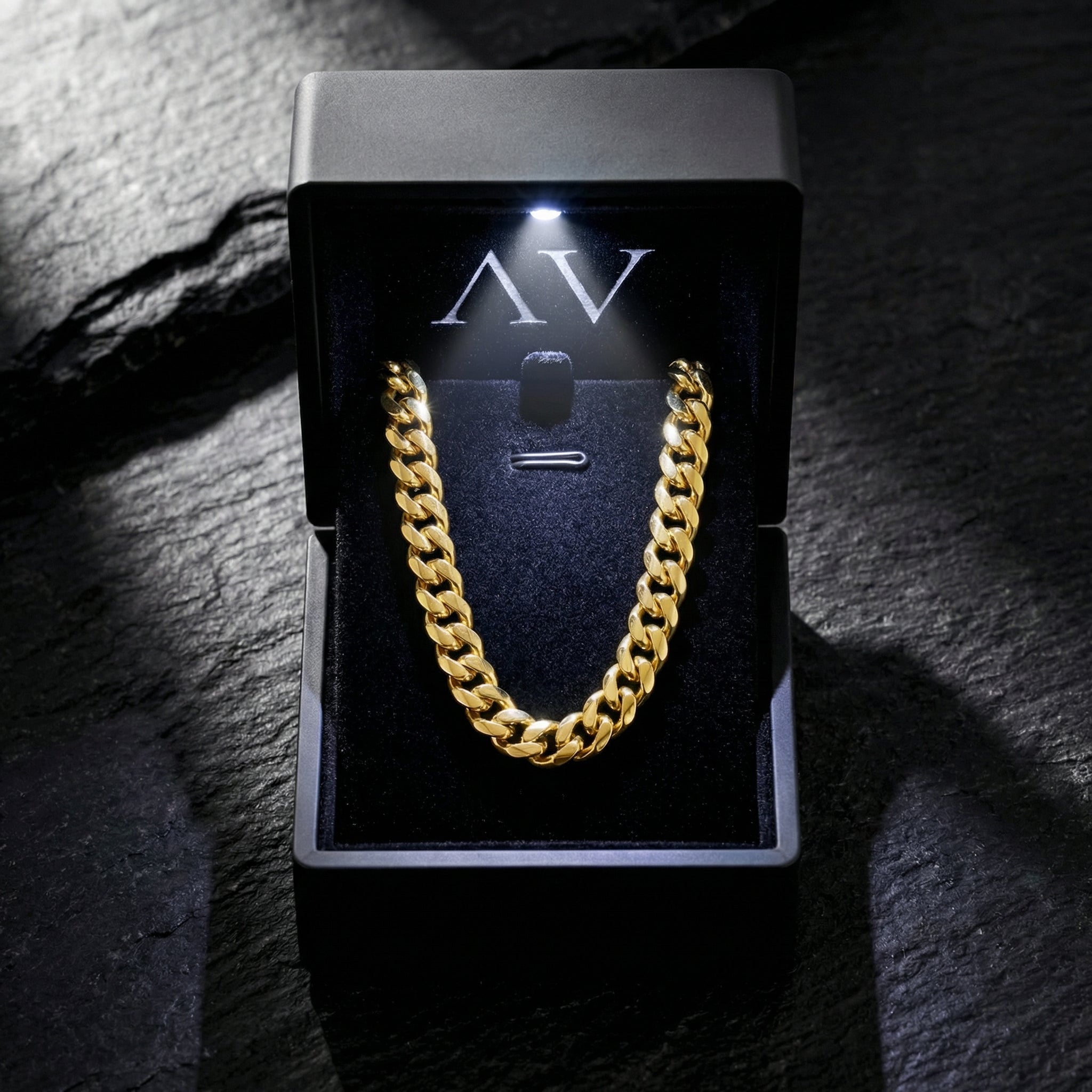 Gold stainless steel Cuban link chain presented in a premium black LED-lit jewelry box with AV branding.